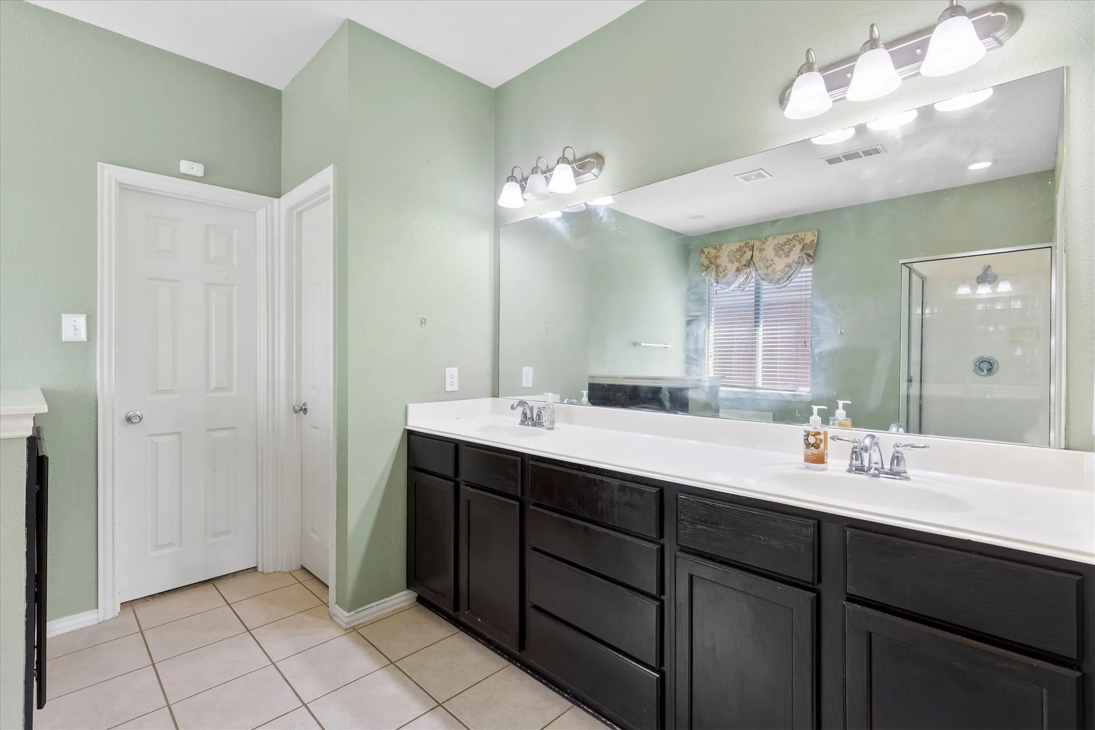 Dual vanity featuring dark wood cabinetry and white countertops