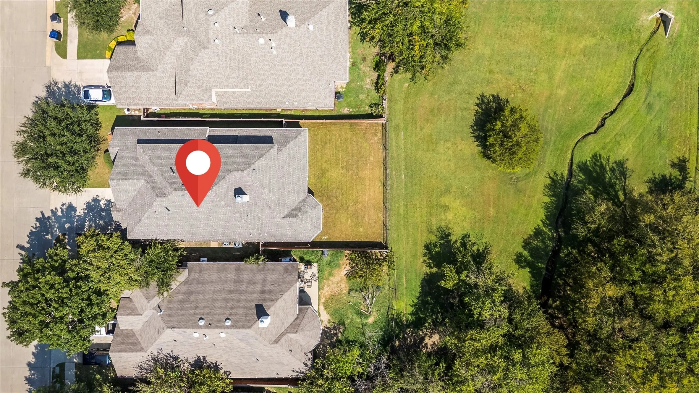 Overhead property view featuring a gabled roofline, a fenced backyard, and surrounding mature trees
