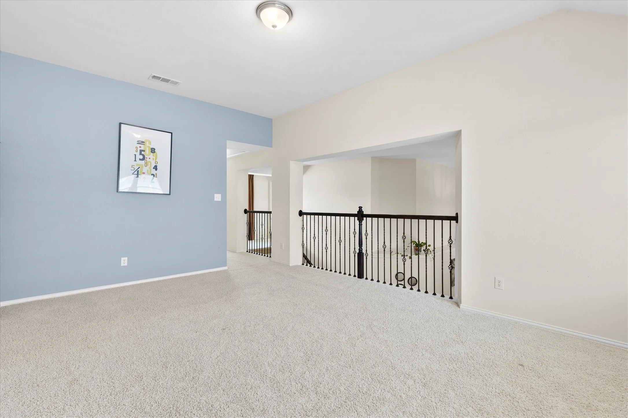Spacious carpeted landing featuring a vaulted ceiling, recessed lighting, and an ornamental metal railing