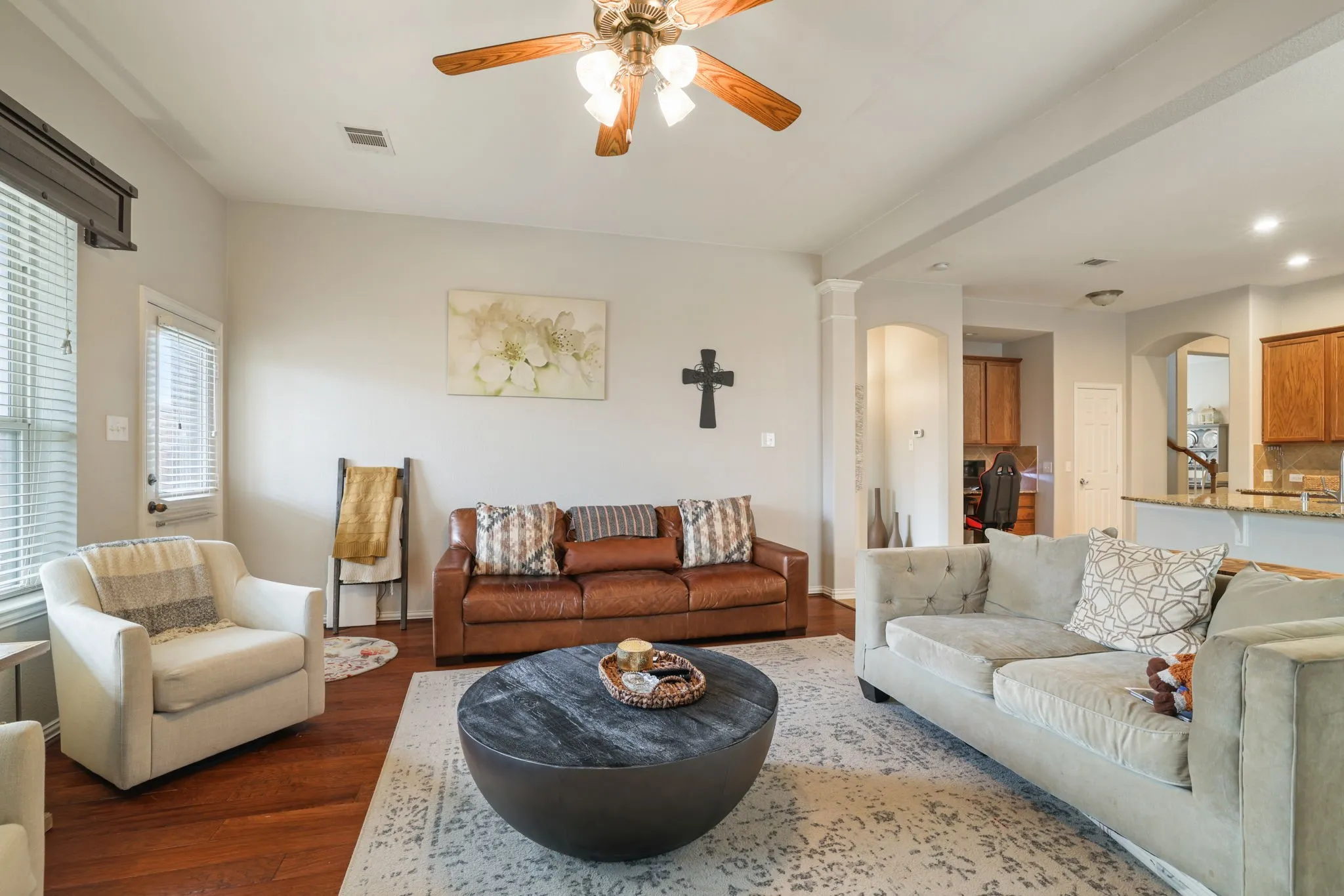 Open-concept living area featuring wood-finish flooring and a ceiling fan with integrated lighting