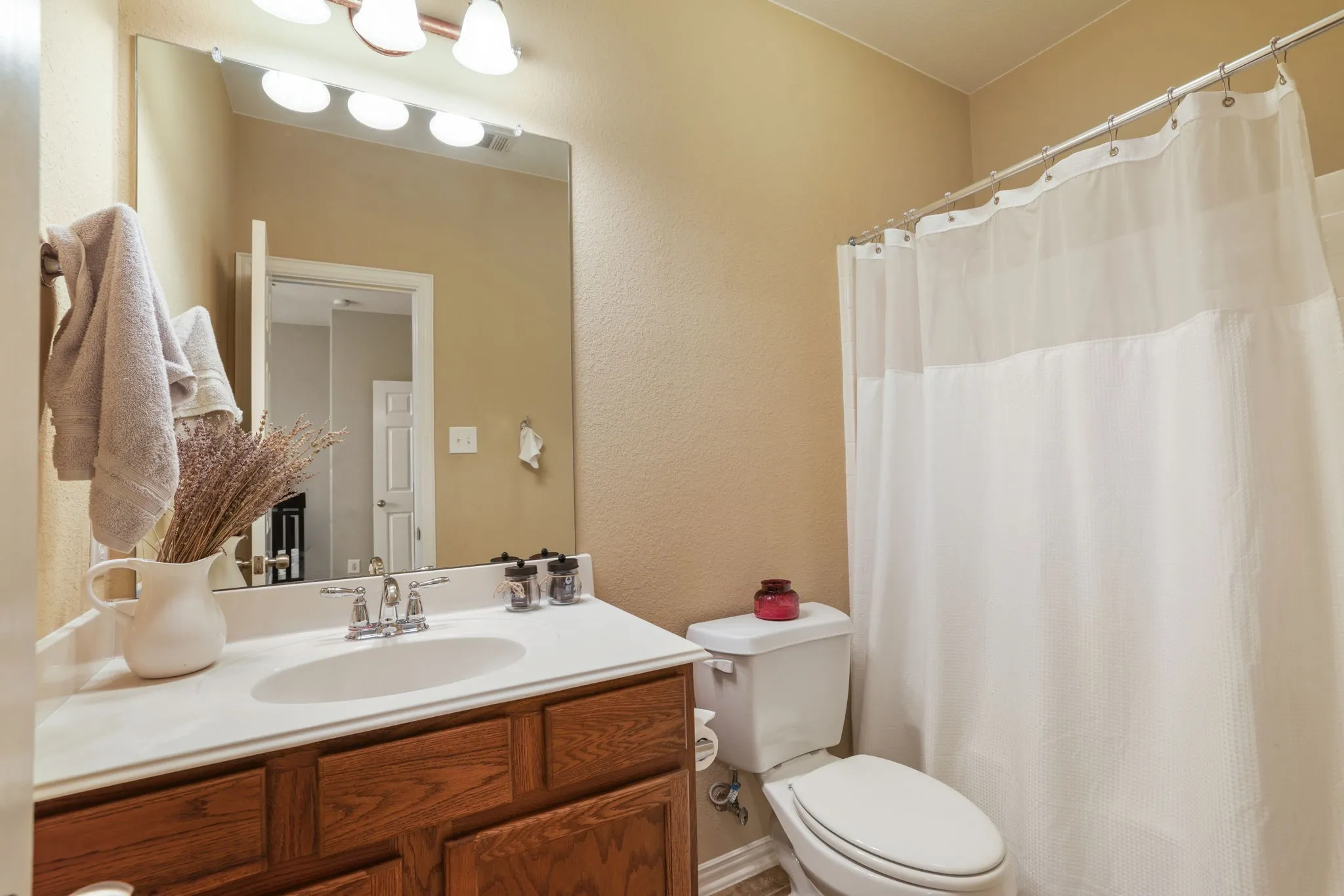 Bathroom featuring a wood-finish vanity with a white countertop and integrated sink, chrome faucet, and a large wall-mounted mirror