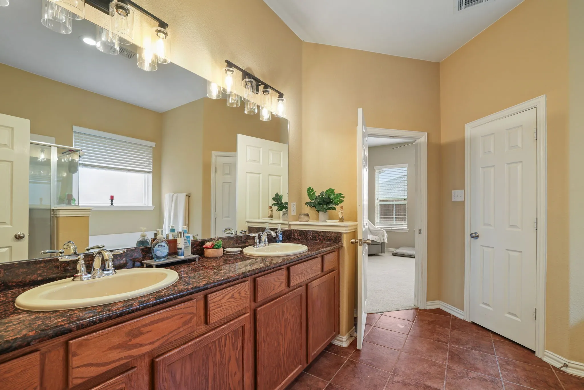 Bathroom featuring a dual vanity with undermount sinks, a brown-toned countertop, and wood-finish cabinetry