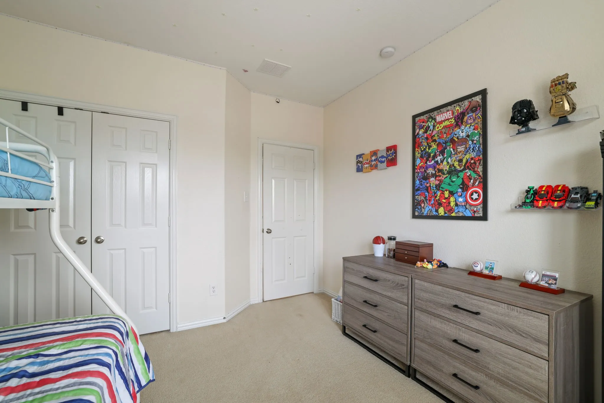 Neutral-toned carpeting grounds this room featuring a pair of white six-panel bifold closet doors and a coordinating six-panel door