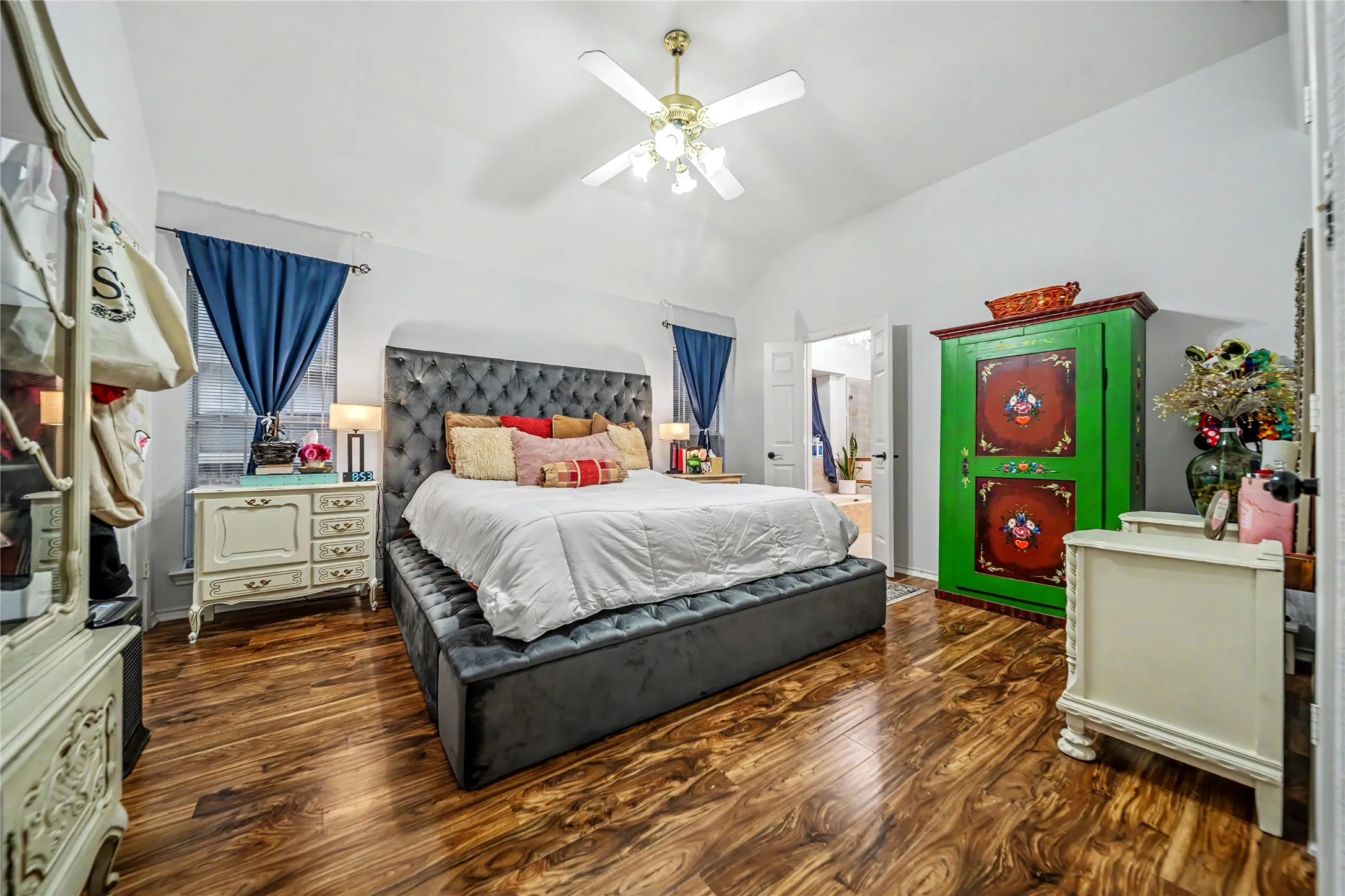 Spacious room featuring vaulted ceilings, wood-finish flooring, and a ceiling fan with integrated lighting