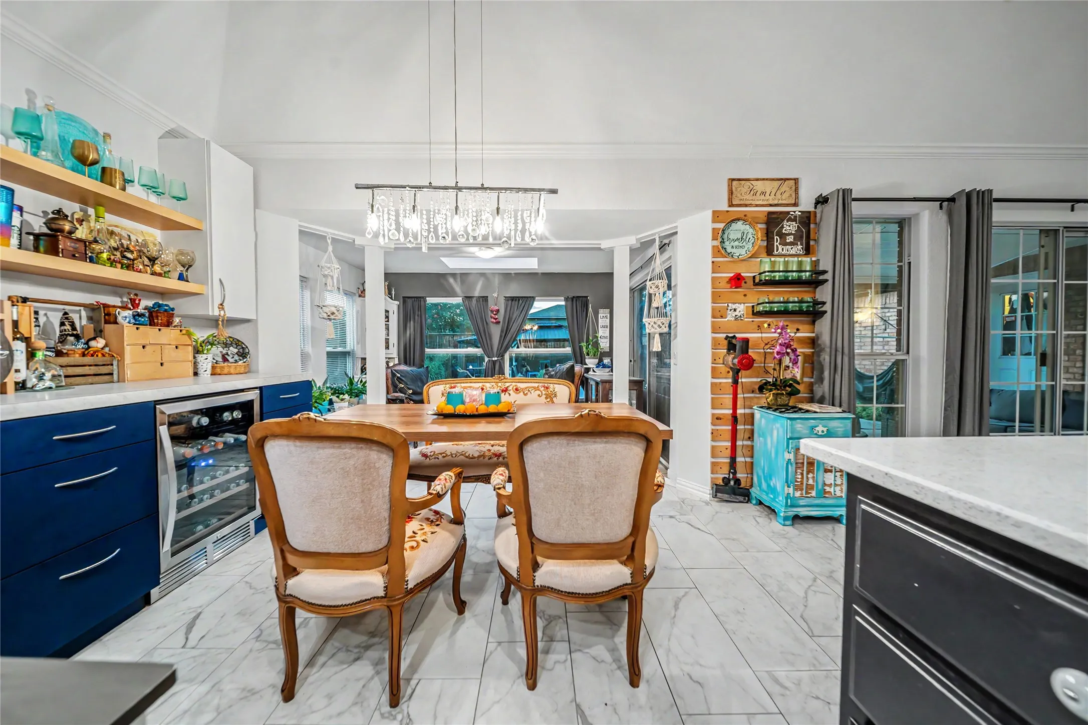 Open-concept kitchen and dining area featuring stone-look tile flooring, a built-in cabinets, white countertops, and a contemporary chandelier
