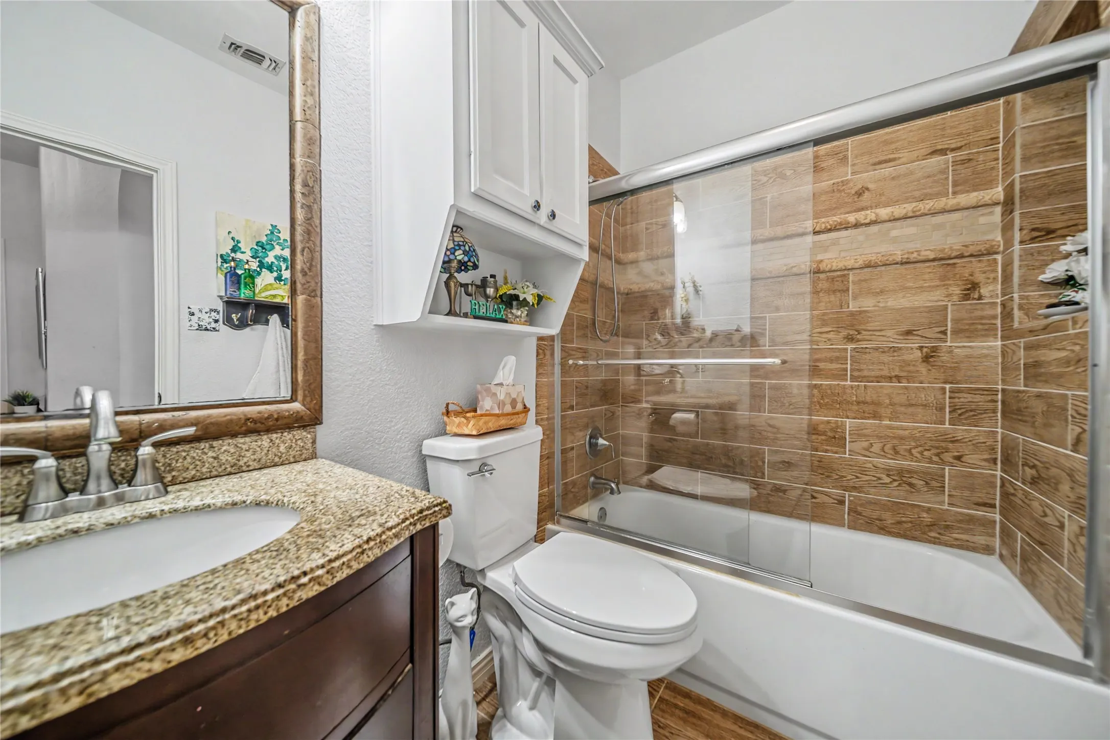 Bathroom featuring a tub/shower combination with sliding glass doors, wood-look tile surround, and a white soaking tub