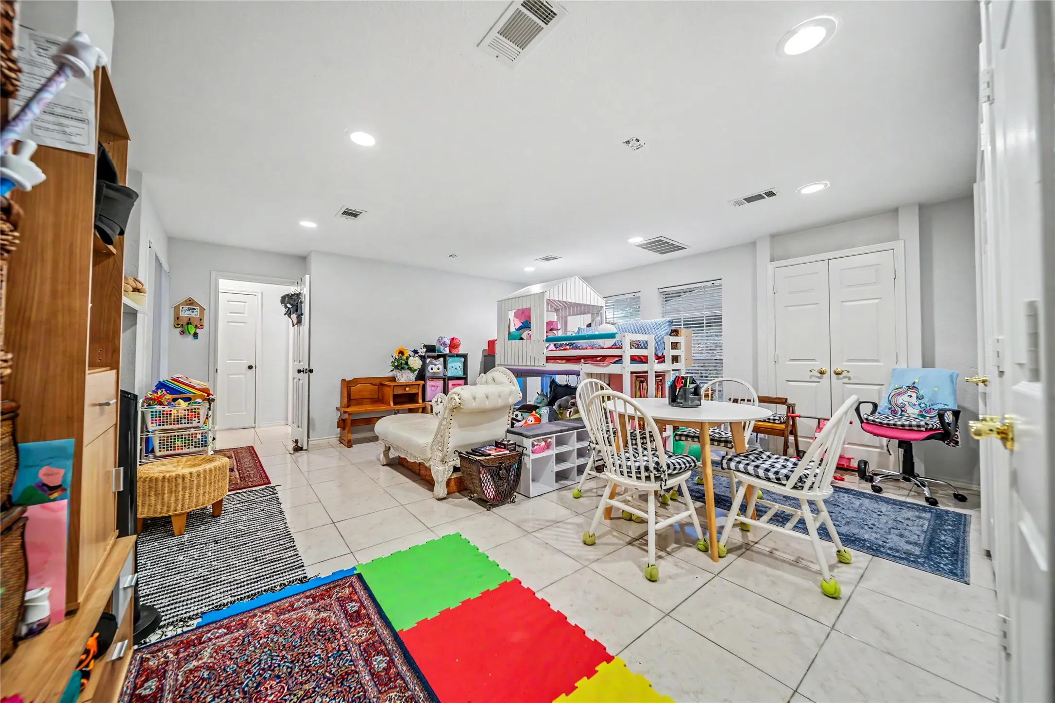 Spacious room featuring light-toned tile flooring, recessed lighting, and multiple windows providing natural illumination