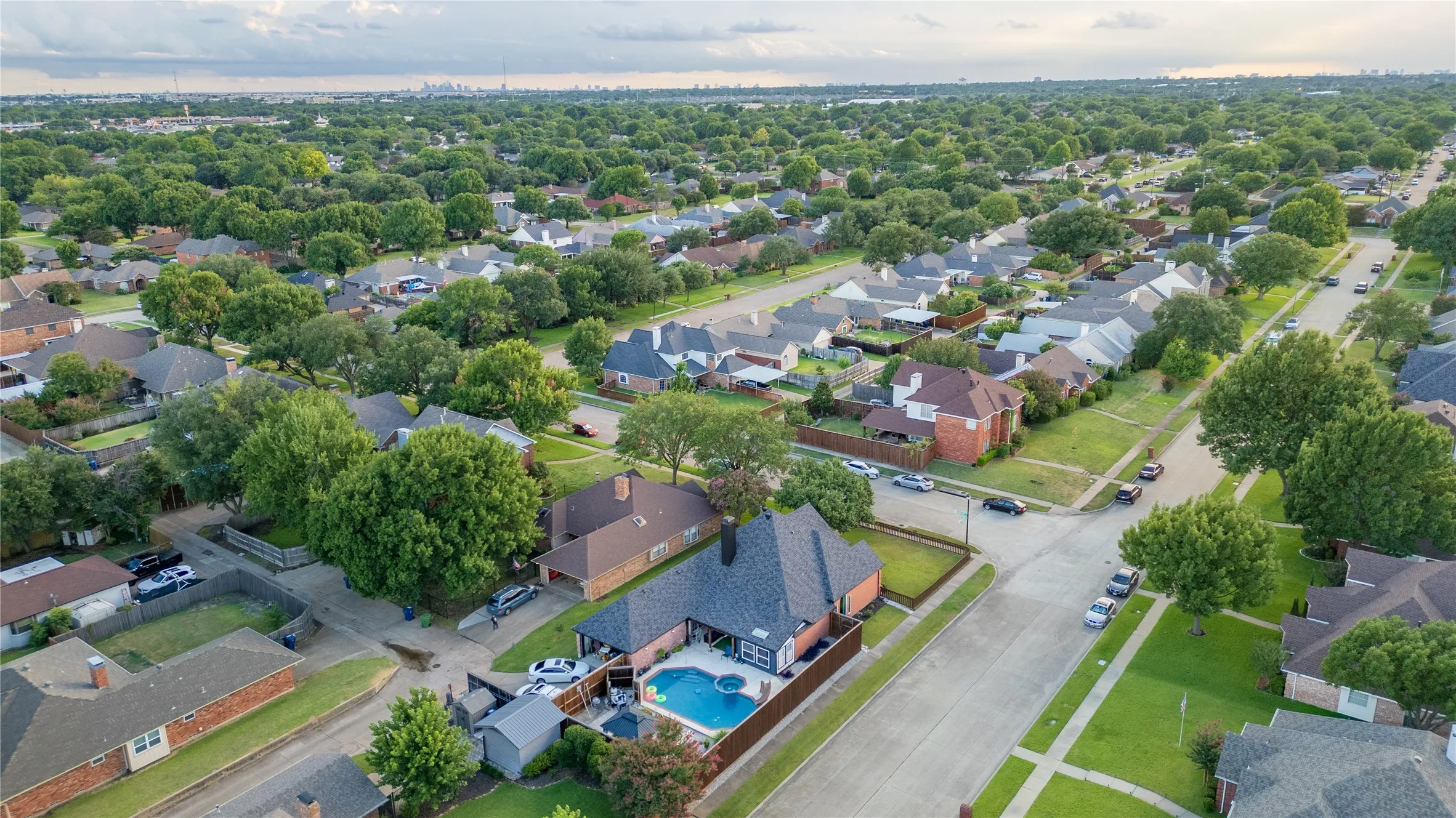 Aerial perspective highlighting the property's private backyard pool, dark shingle roofing, and brick exterior
