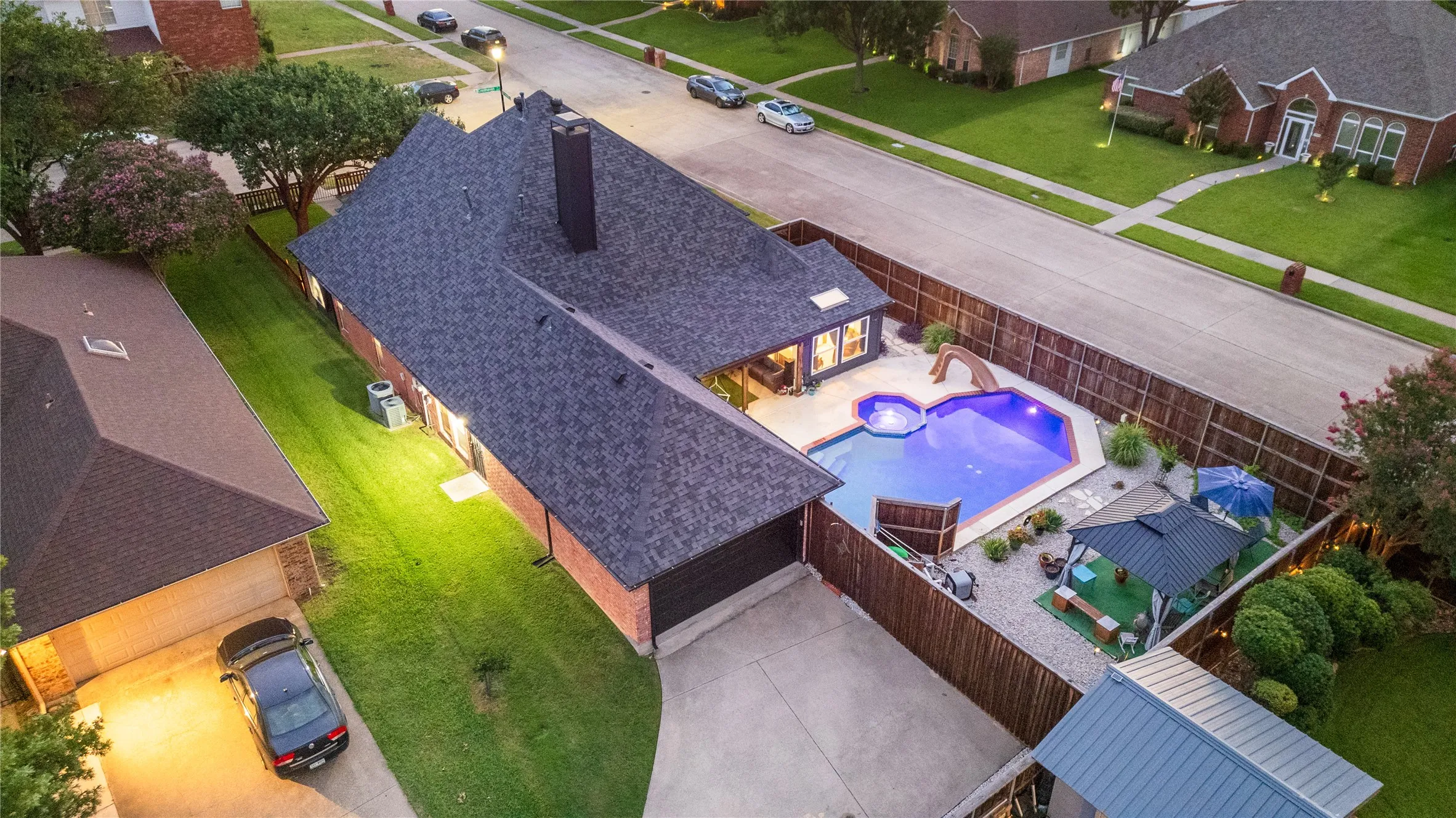 Backyard oasis featuring a fenced in-ground pool with slide, spa, and integrated lighting