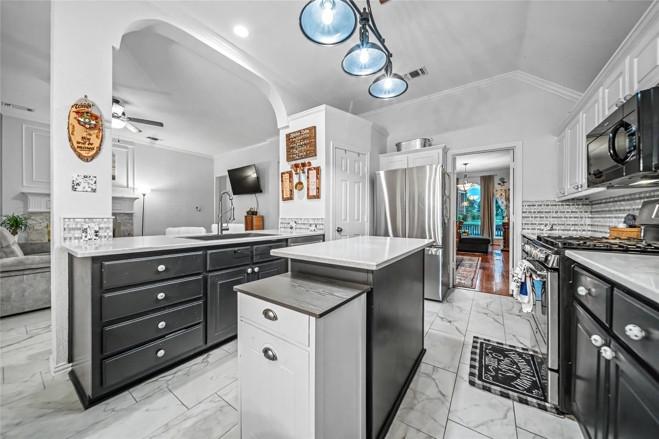 Kitchen featuring two-tone cabinetry, a central island with white countertop, stainless steel refrigerator, and tiled flooring