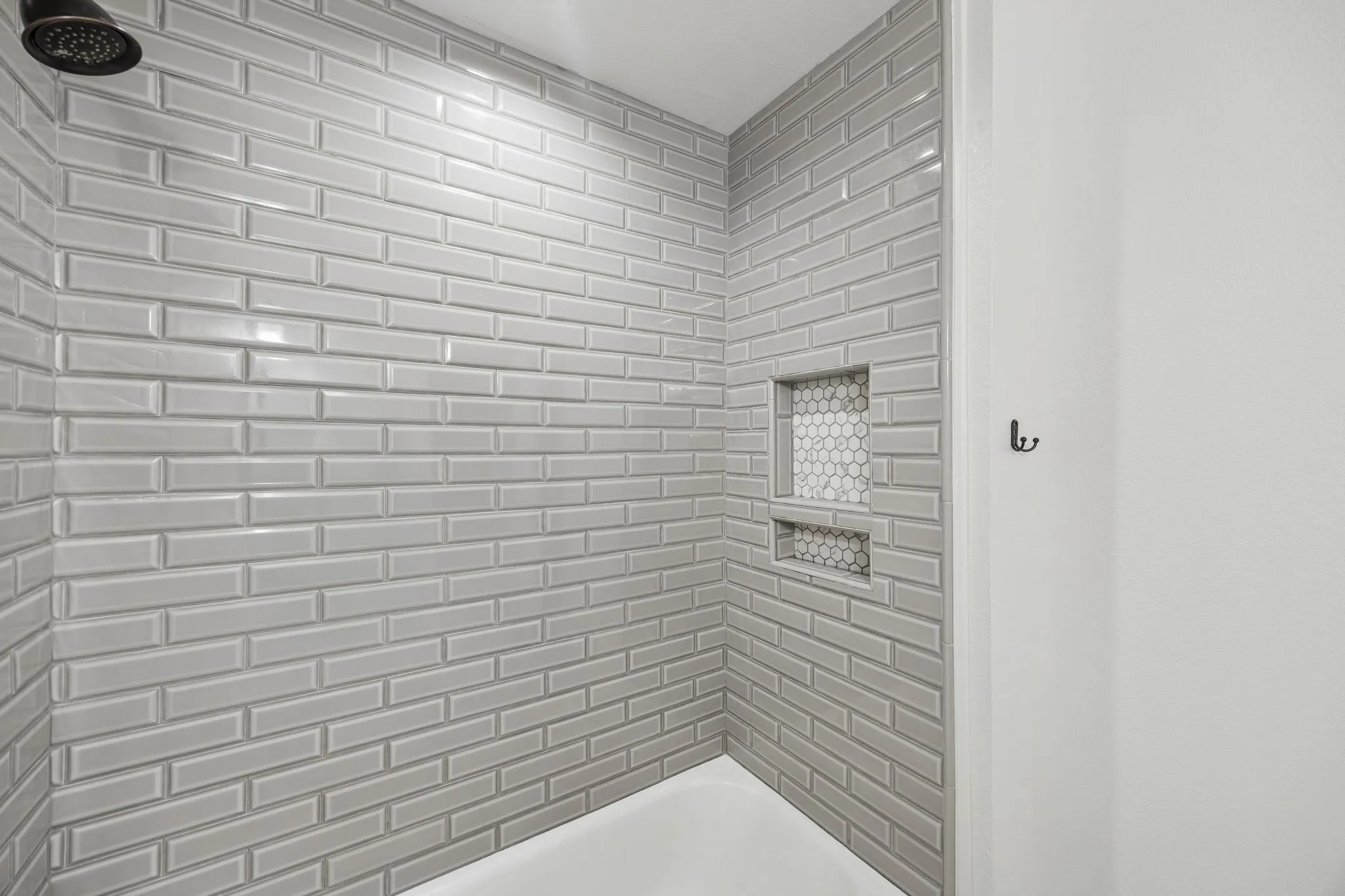 Gray subway tile laid in a classic brick pattern gives the renovated guest shower a clean and timeless finish.