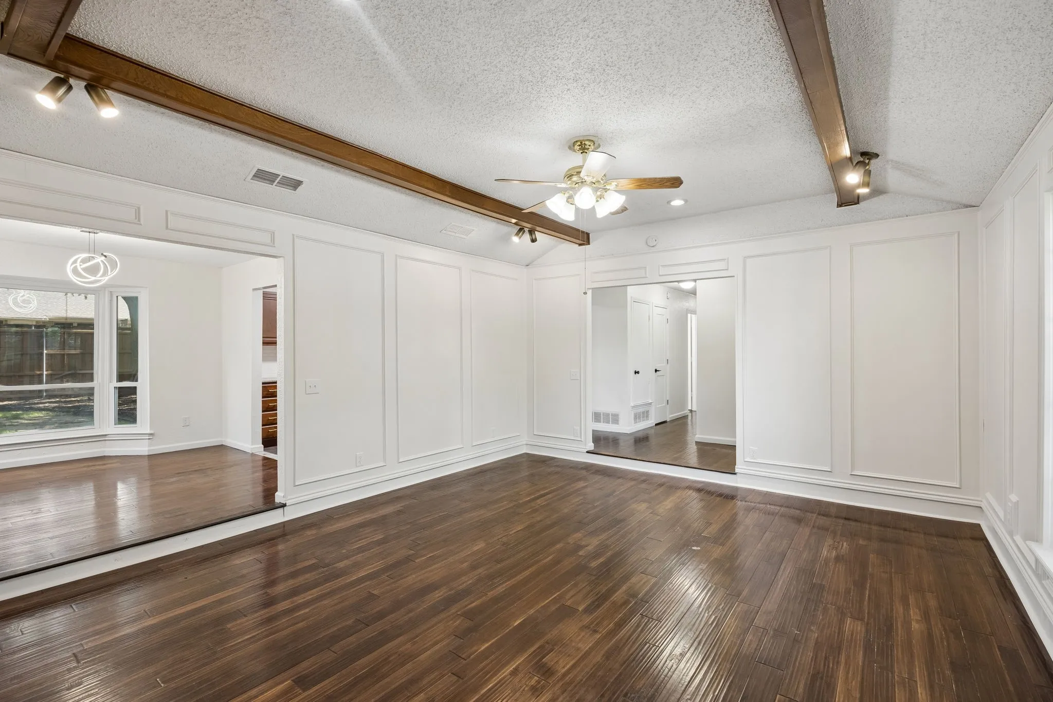 This alternate view highlights the family room’s generous proportions, hardwood flooring and connection to the adjoining spaces.