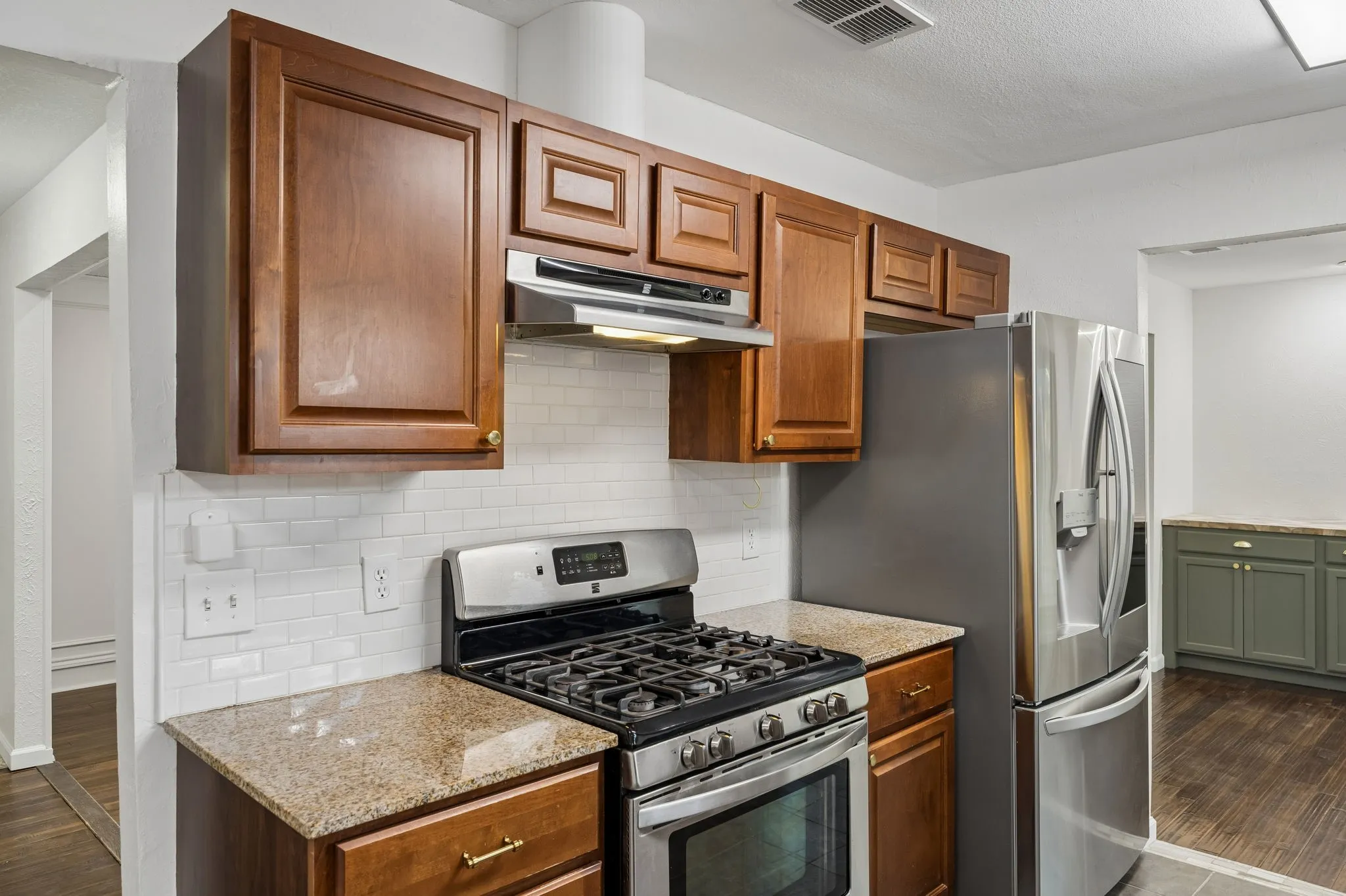 Warm wood cabinetry provides generous storage, while updated counters, backsplash and appliances add practical appeal.