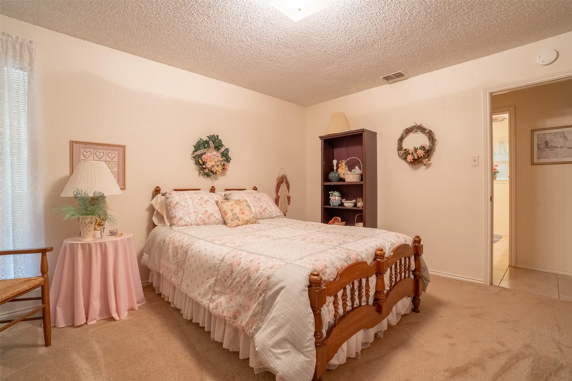 Carpeted room featuring a window with sheer curtains, a built-in light fixture, and a doorway leading to an additional space