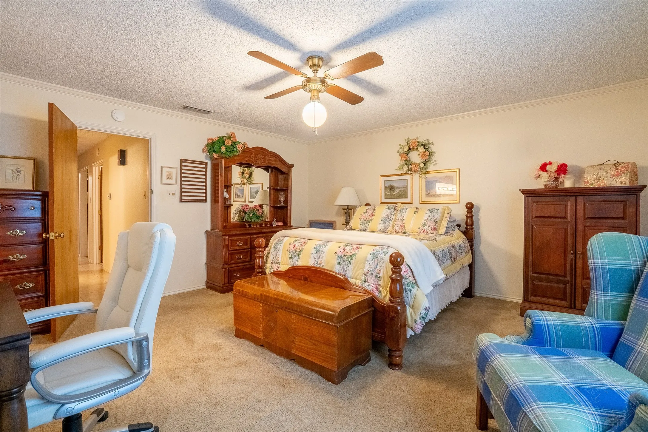 Carpeted bedroom featuring a ceiling fan with light fixture, light-toned walls, and a wooden door