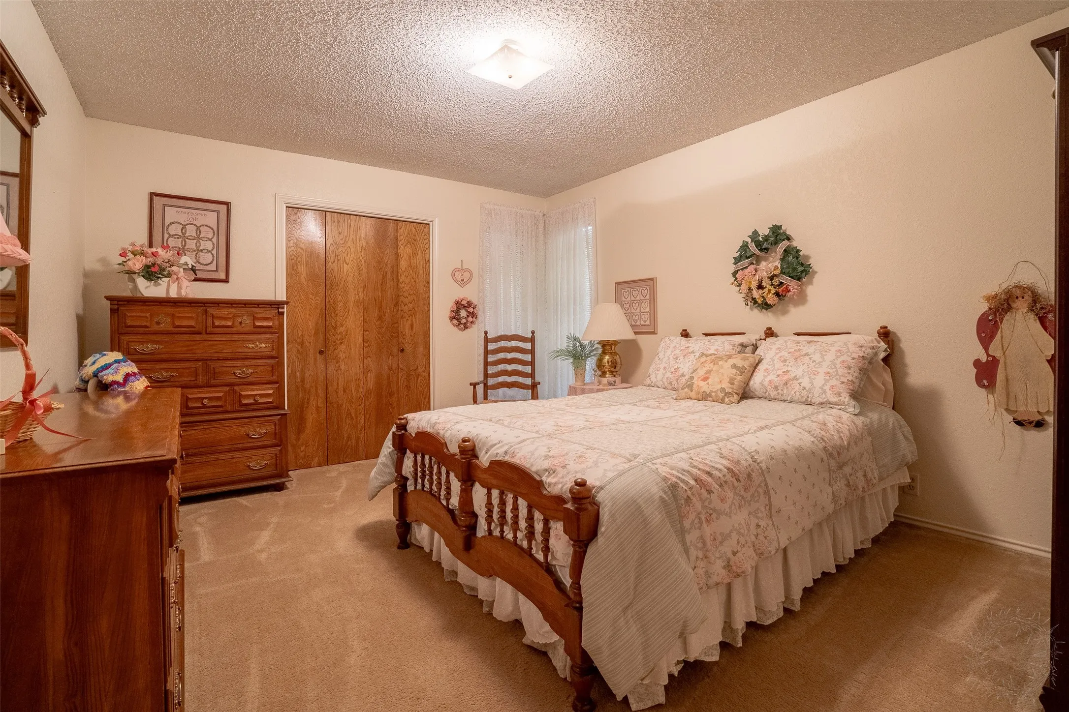 Carpeted bedroom featuring a wood-finish closet with bi-fold doors, neutral wall tones, and a ceiling-mounted light fixture