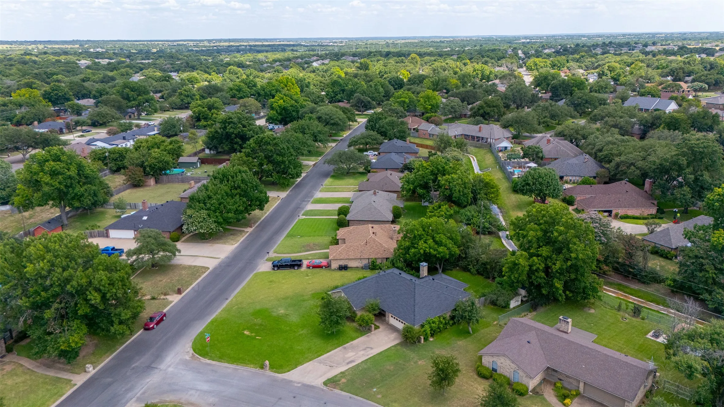 Residential neighborhood featuring mature trees, paved streets, and varied single-family homes with pitched roofs