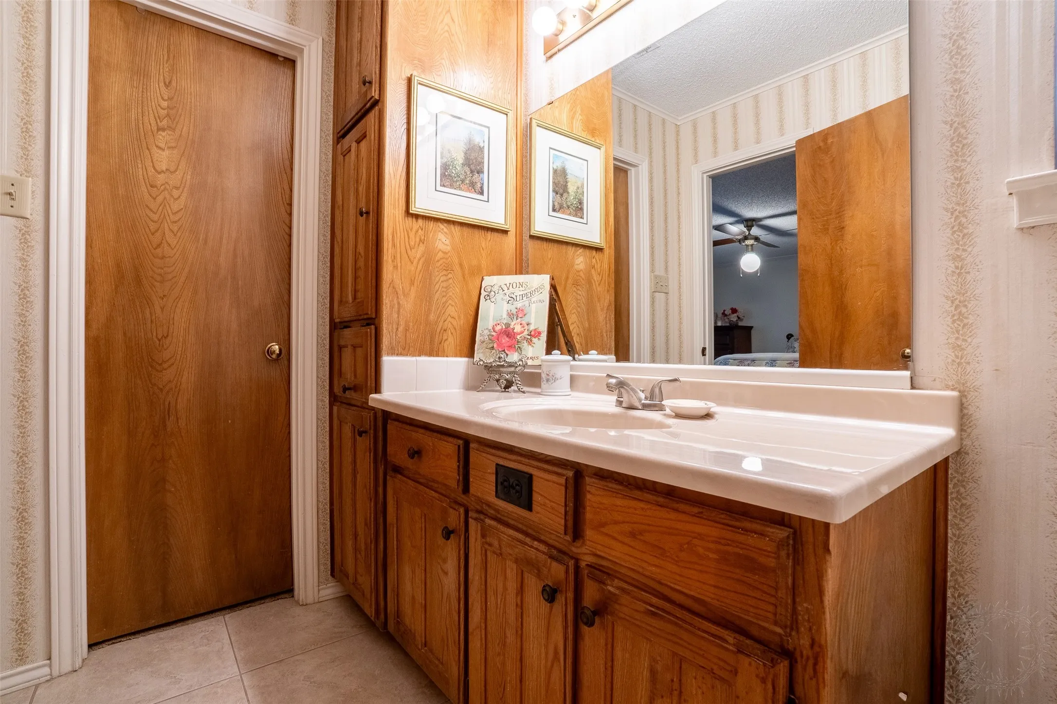 Bathroom vanity featuring a light-colored countertop with an integrated sink, wood-finish cabinetry, and a framed mirror