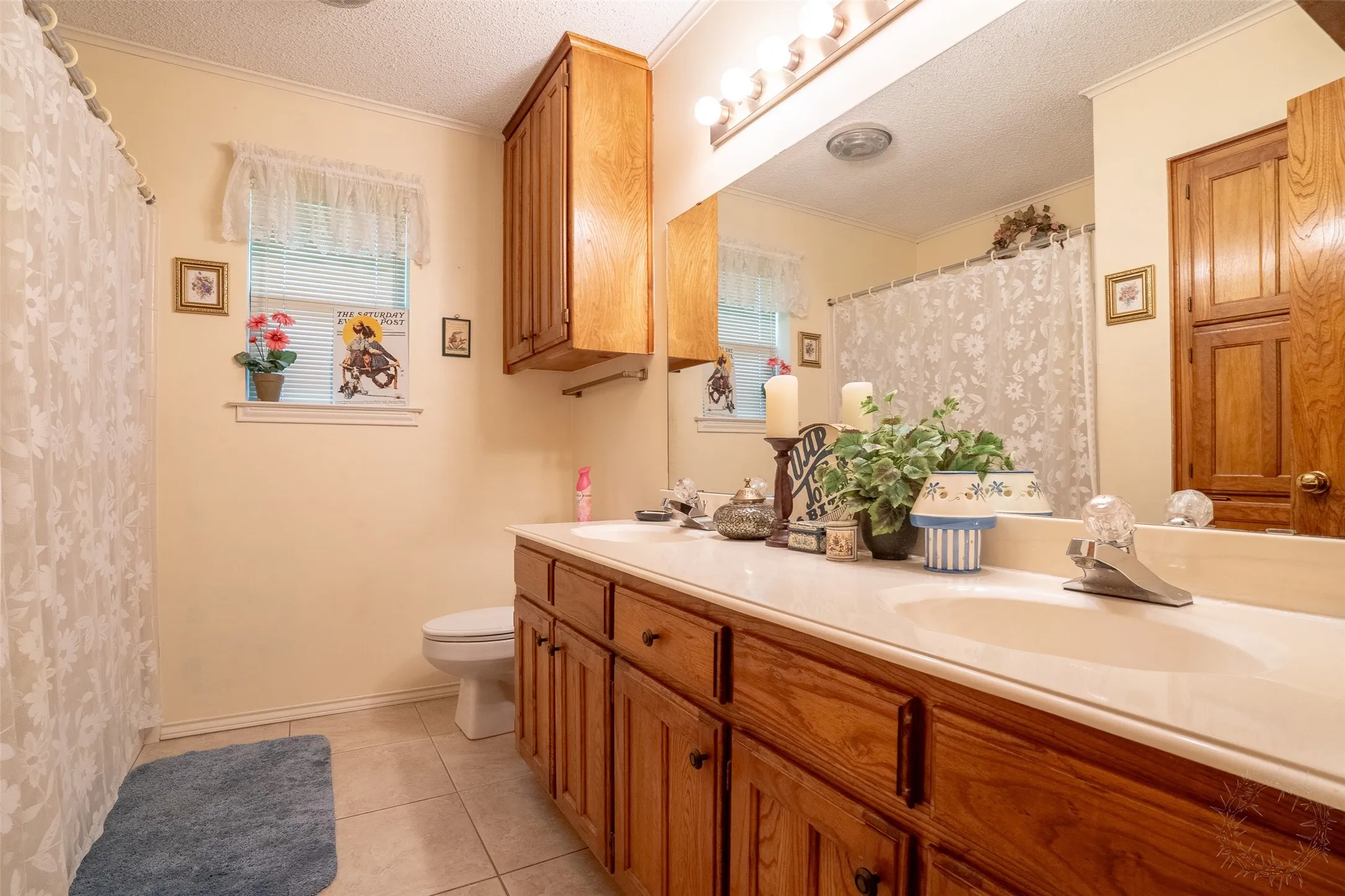 Bathroom featuring a double vanity with wood-finish cabinetry, integrated sinks, and a large wall-mounted mirror