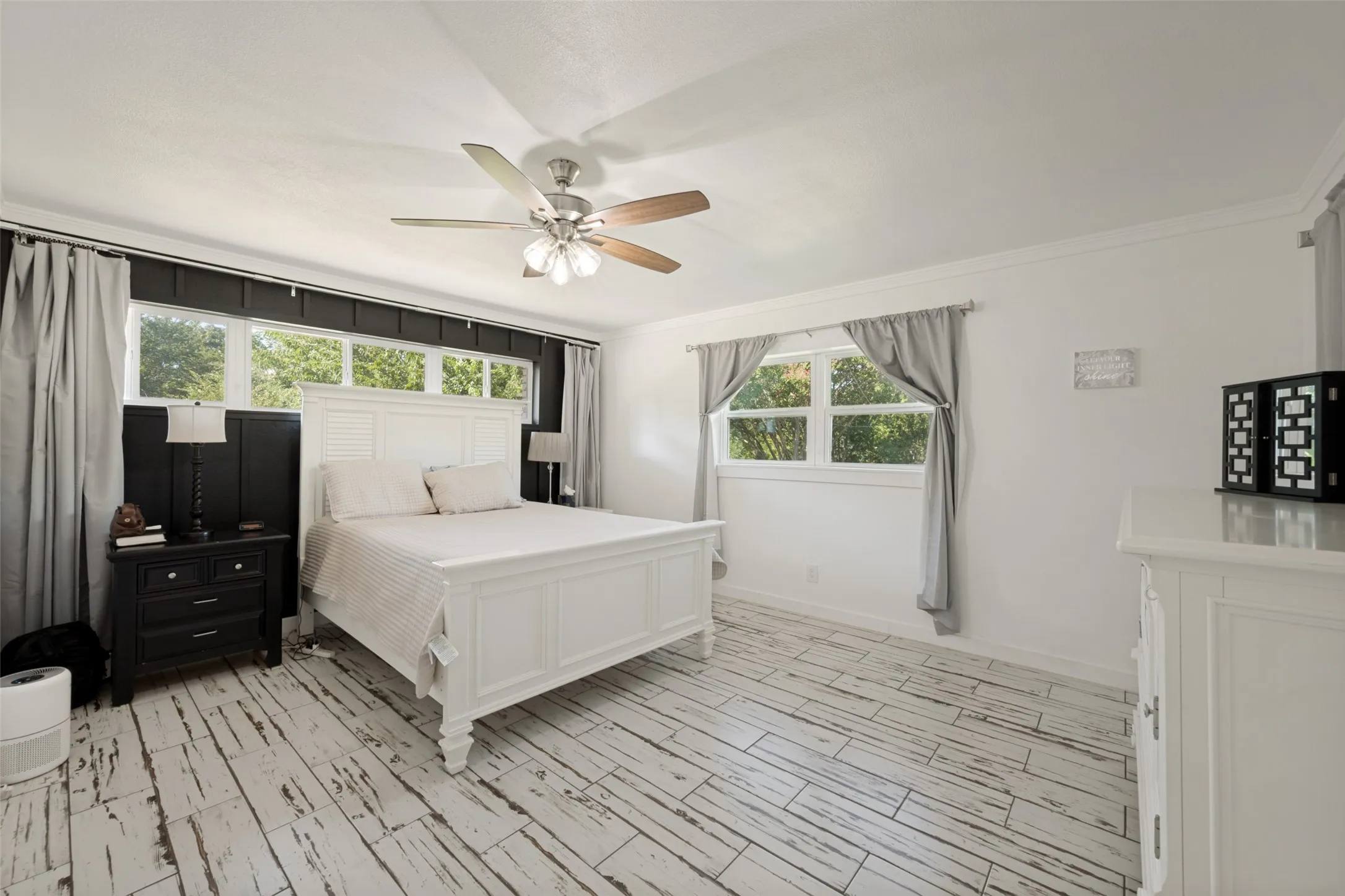 Spacious room featuring distressed wood-look flooring, white walls, and a ceiling fan with integrated lighting