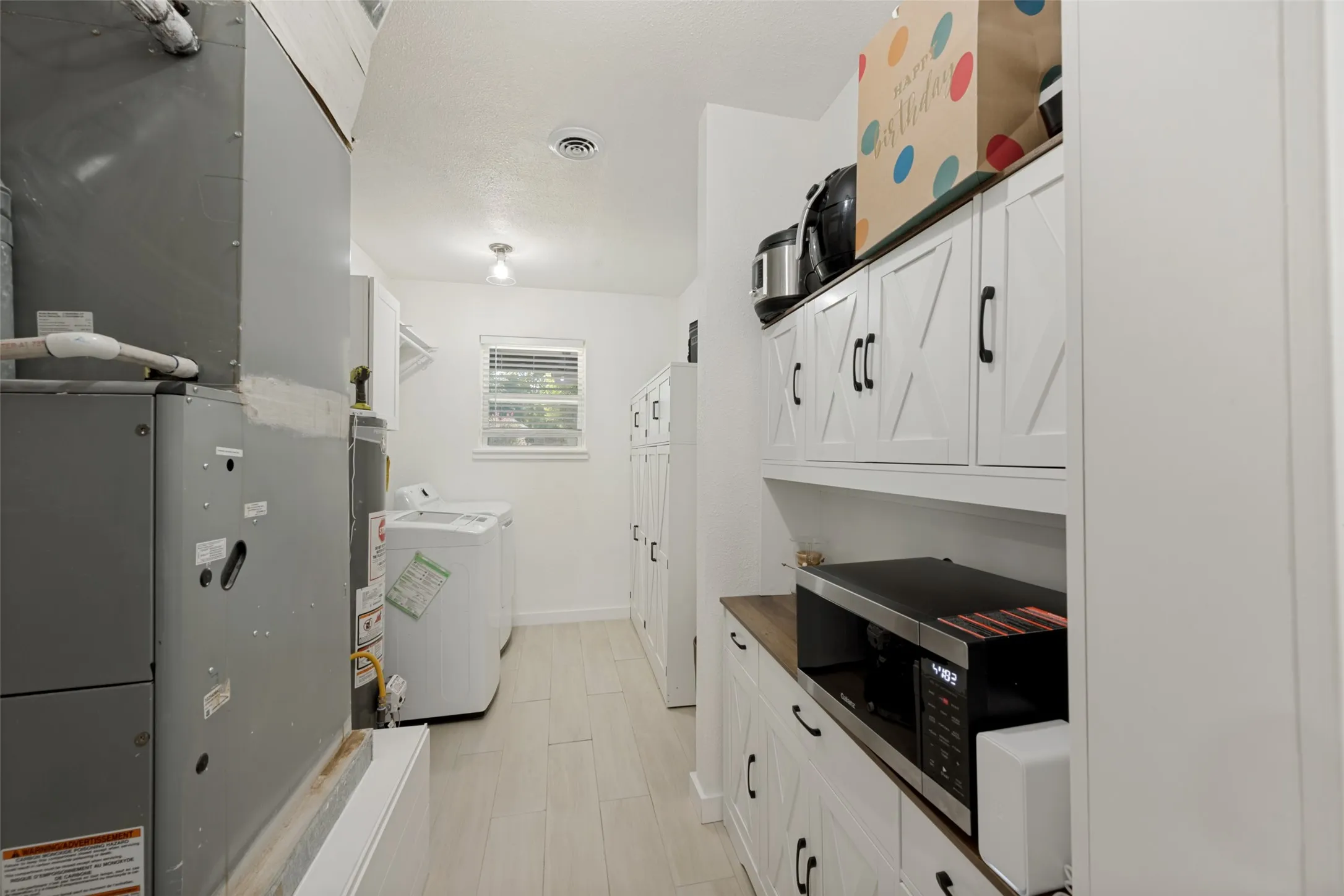 Utility area featuring a built-in pantry with white shaker-style cabinetry, wood-finish countertops
