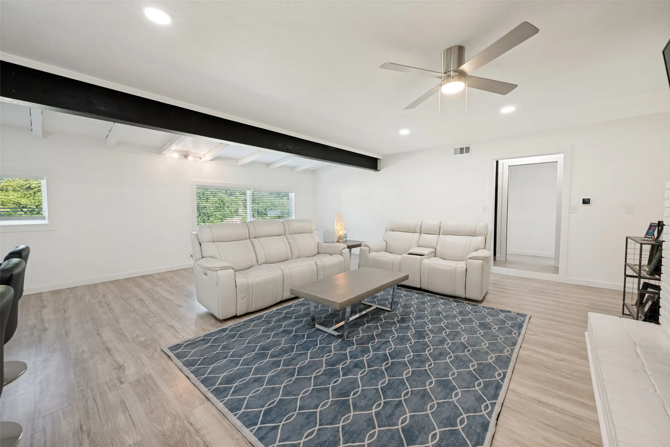 Spacious living area featuring light wood-look flooring, recessed lighting, and a contemporary ceiling fan