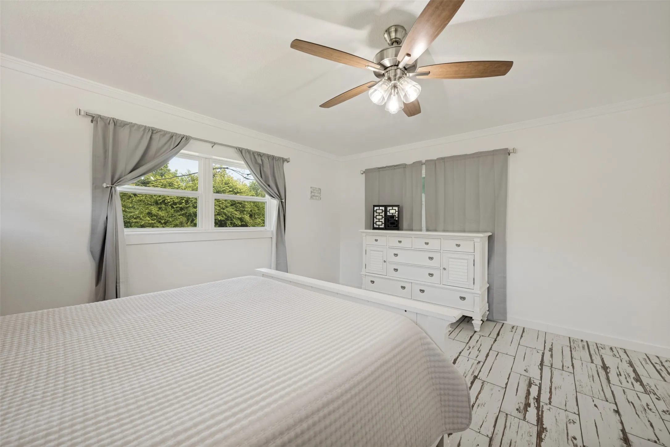 Room featuring light flooring, a ceiling fan with light fixture, and crown molding