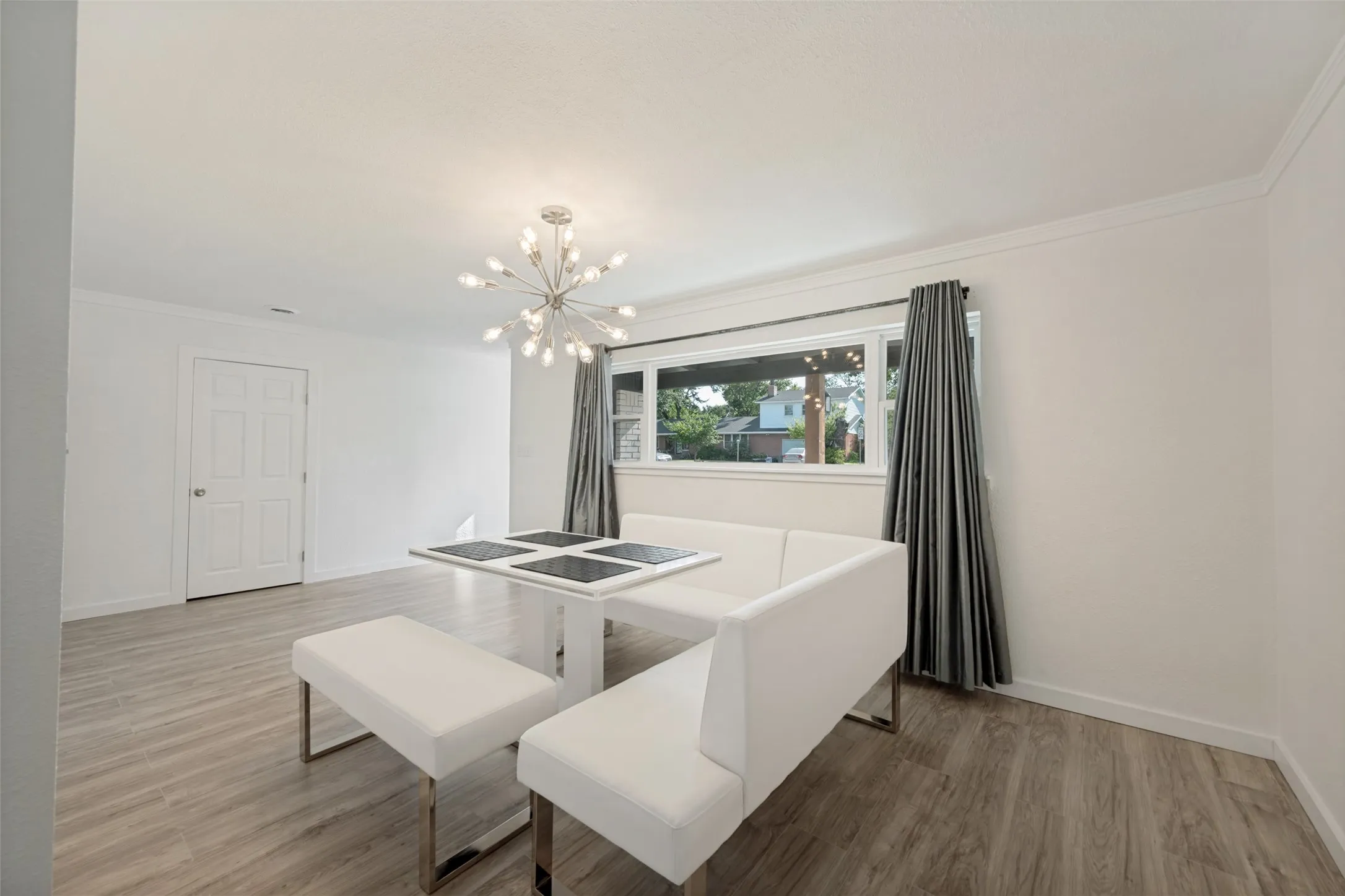 Bright interior space featuring wood-look flooring, a contemporary sputnik chandelier, and a large window with white trim