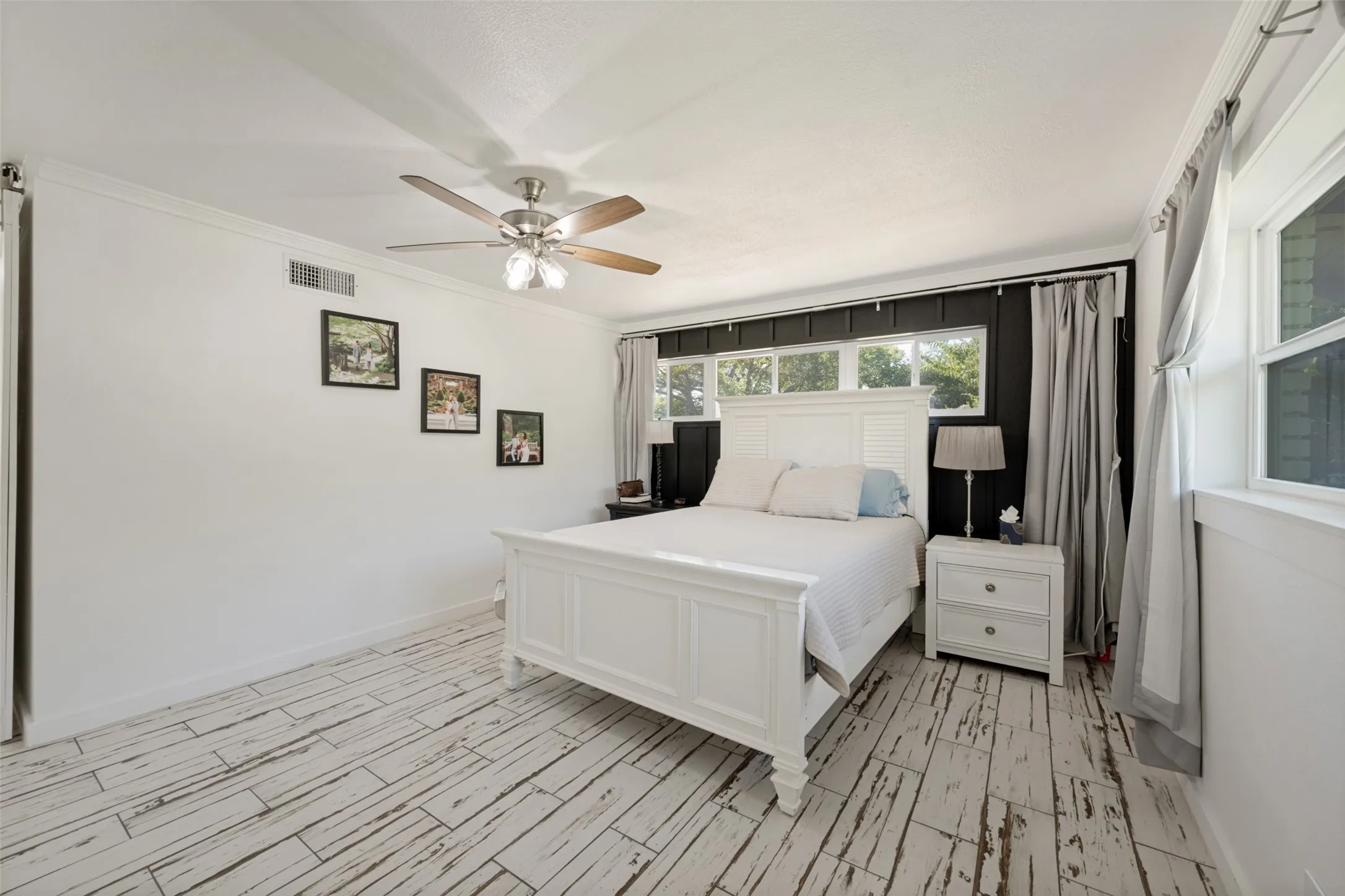 Bedroom featuring wood-look flooring, a ceiling fan, and multiple windows with white trim
