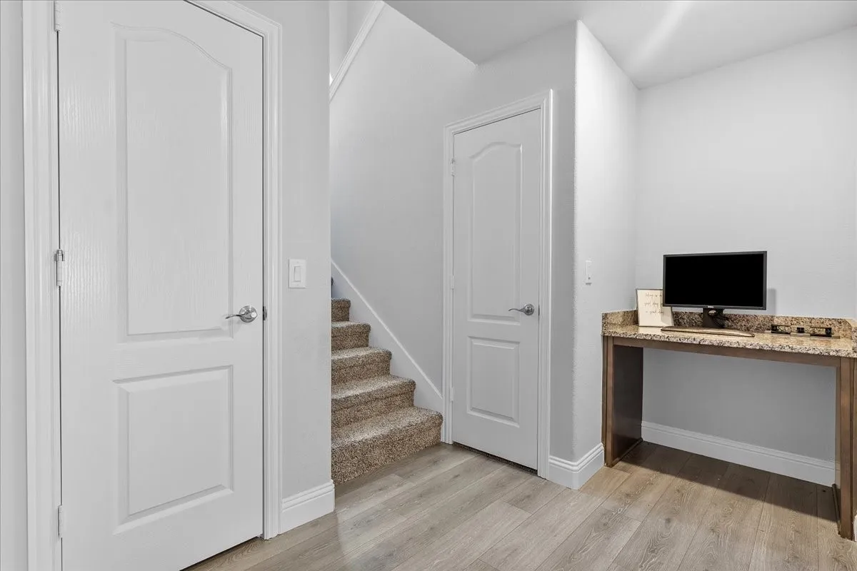 Built-in desk area featuring a stone countertop, light wood-finish flooring, and white trim molding