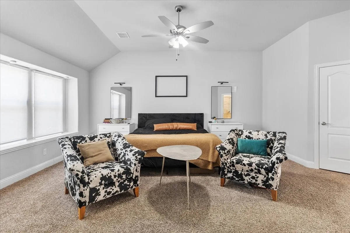 Spacious room featuring vaulted ceilings and neutral-toned carpeting