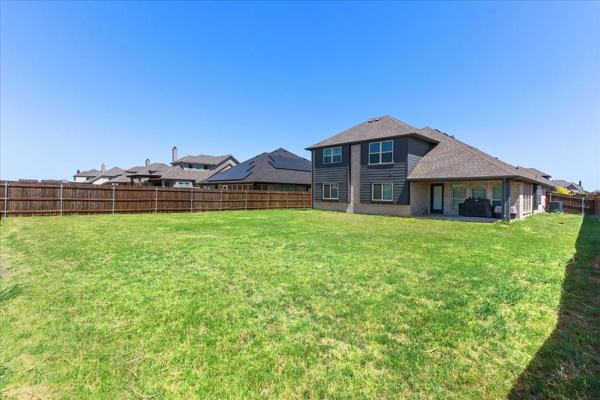 Expansive fenced backyard with a large grass area