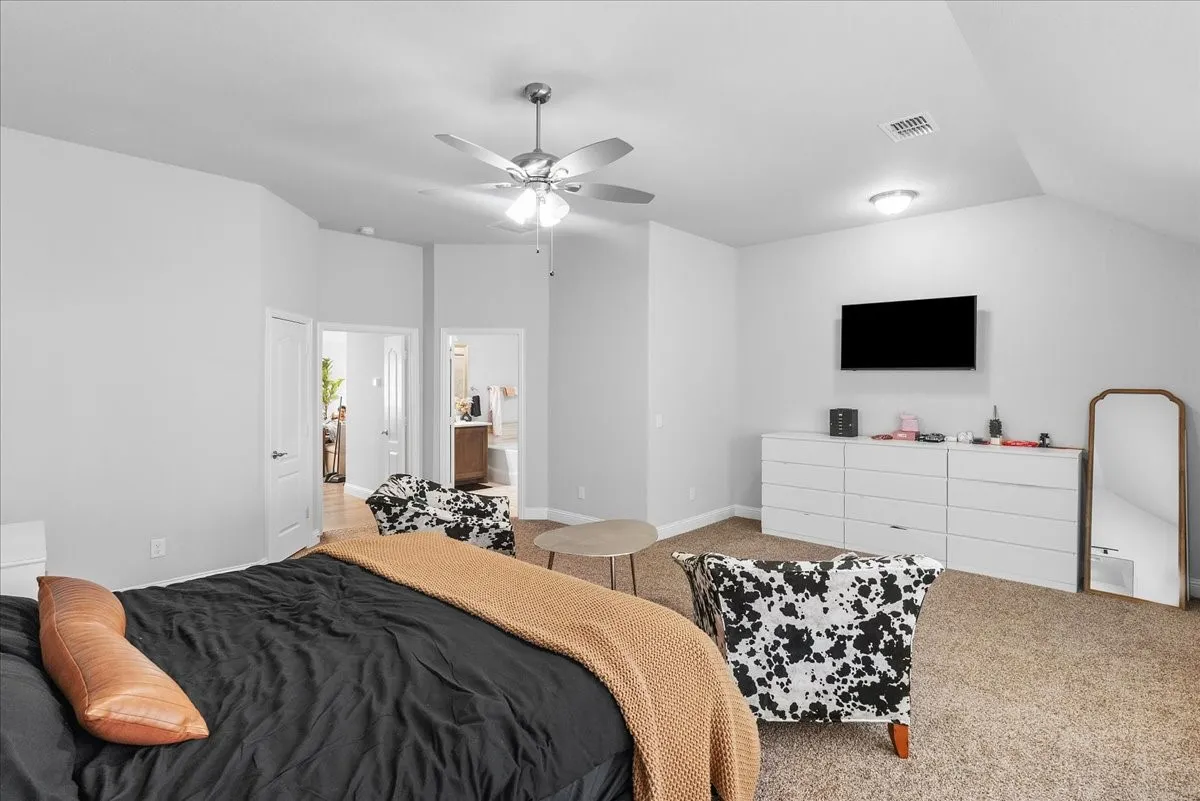 Spacious carpeted room featuring a ceiling fan with integrated lighting, multiple white panel doors, and a wall-mounted flush light fixture