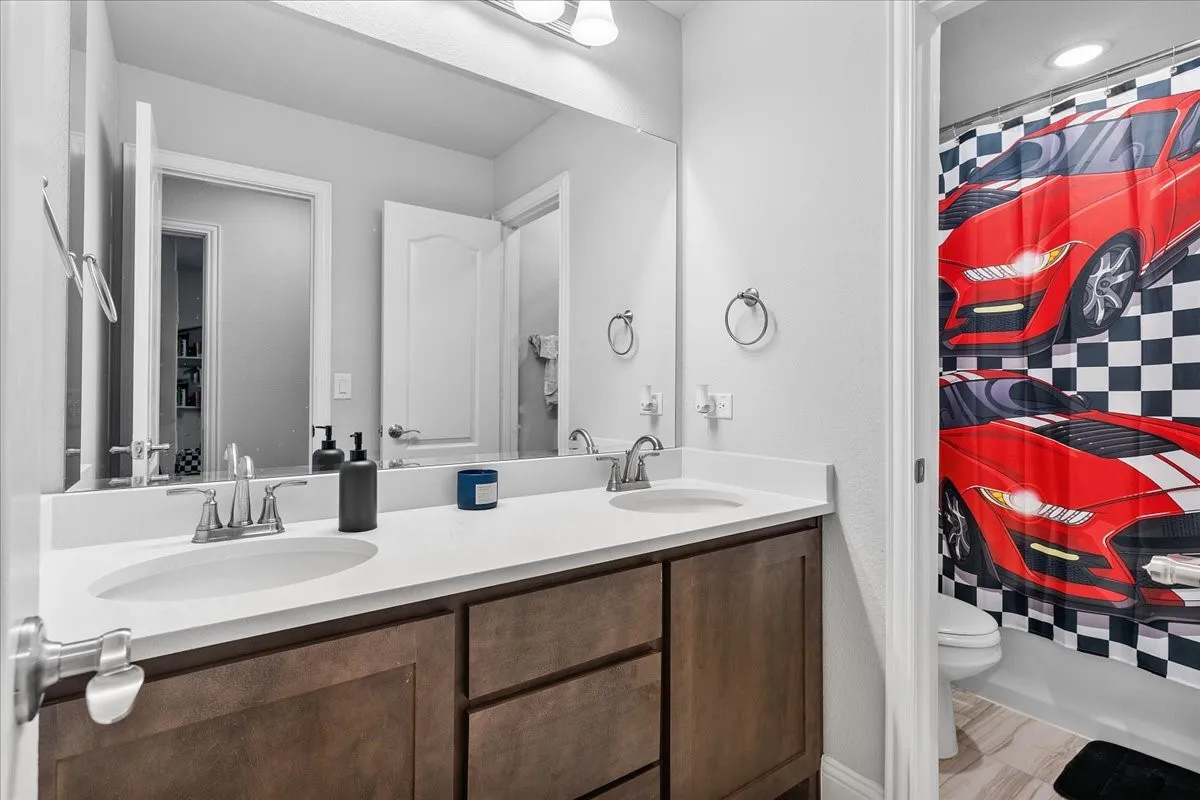 Dual vanity with integrated sinks, white countertops, and wood-finish cabinetry