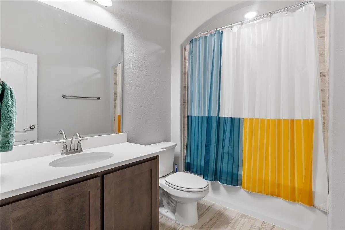 Vanity featuring a white countertop with an undermount sink, brushed nickel faucet, and wood-finish cabinetry