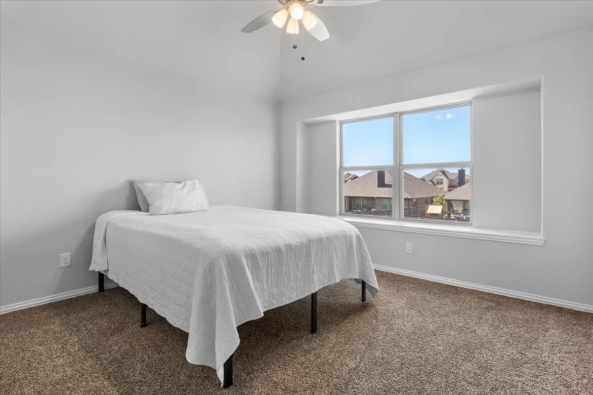 Carpeted room featuring a ceiling fan with light fixture, light gray walls, a window with a deep sill, and white trim
