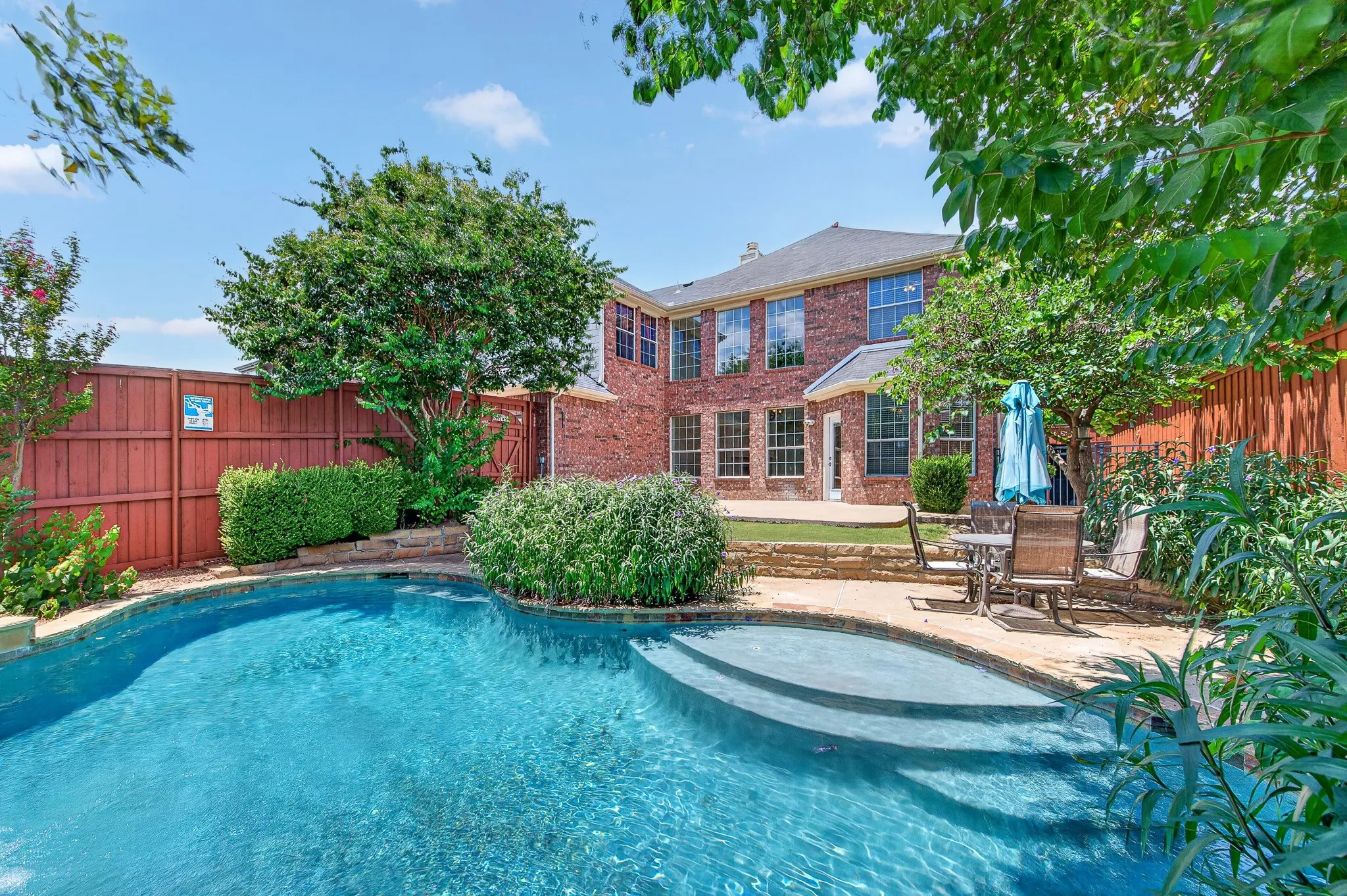 Brick exterior property featuring a fenced backyard with a swimming pool, integrated spa, and an adjacent patio area