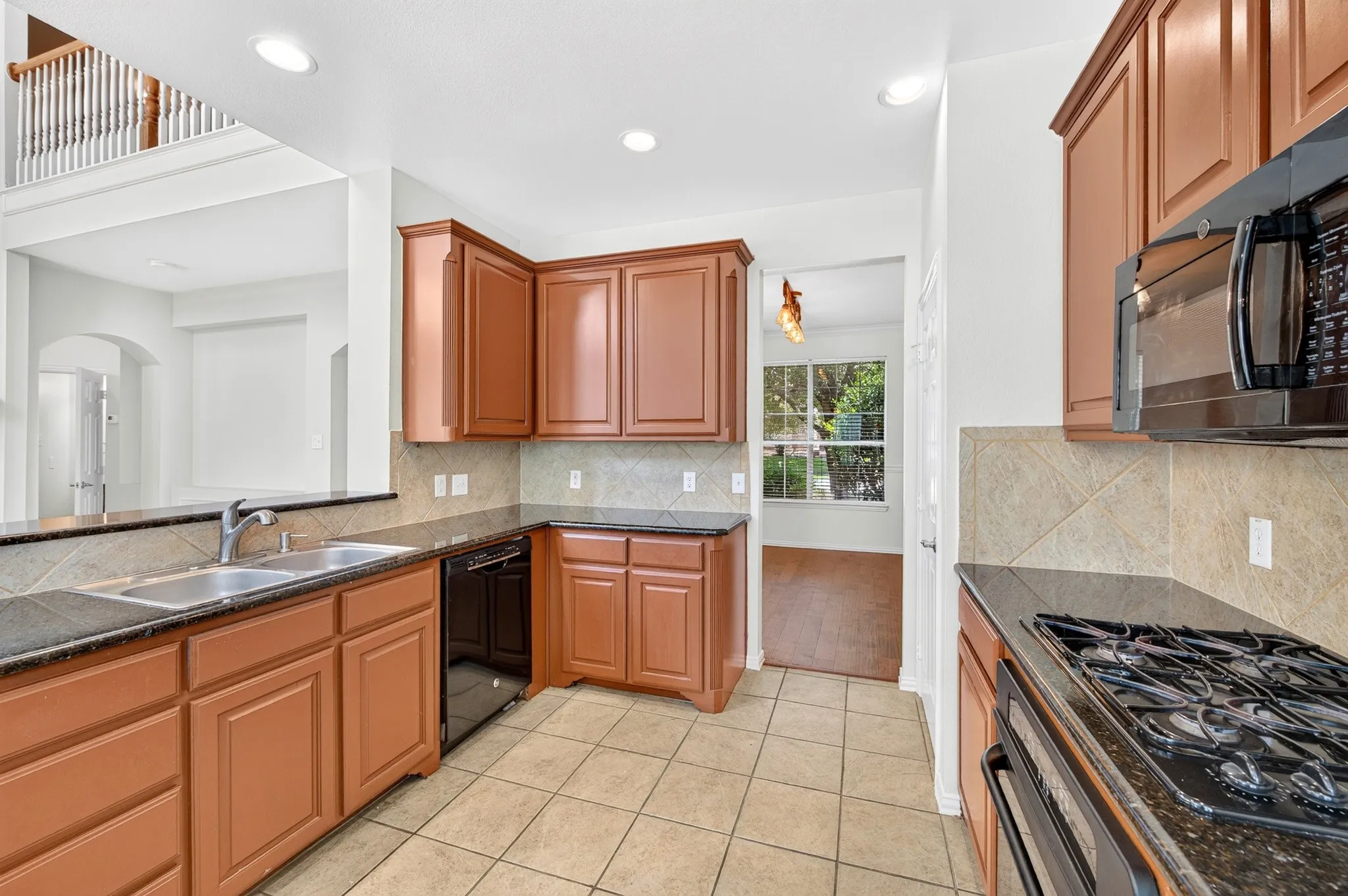 Kitchen featuring wood cabinetry, dark countertops, a double basin sink, and a built-in microwave
