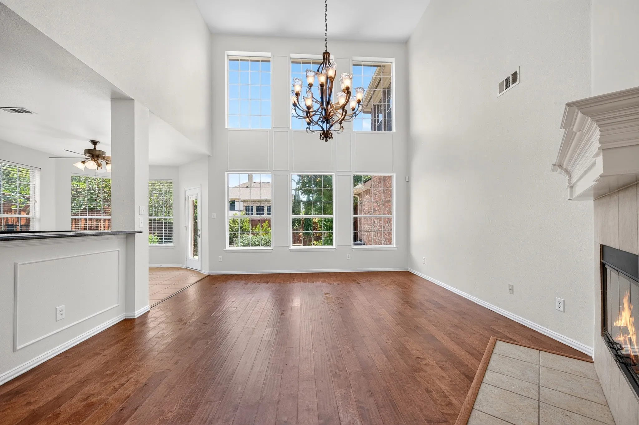 Two-story living area featuring wood-finish flooring and a tiered chandelier