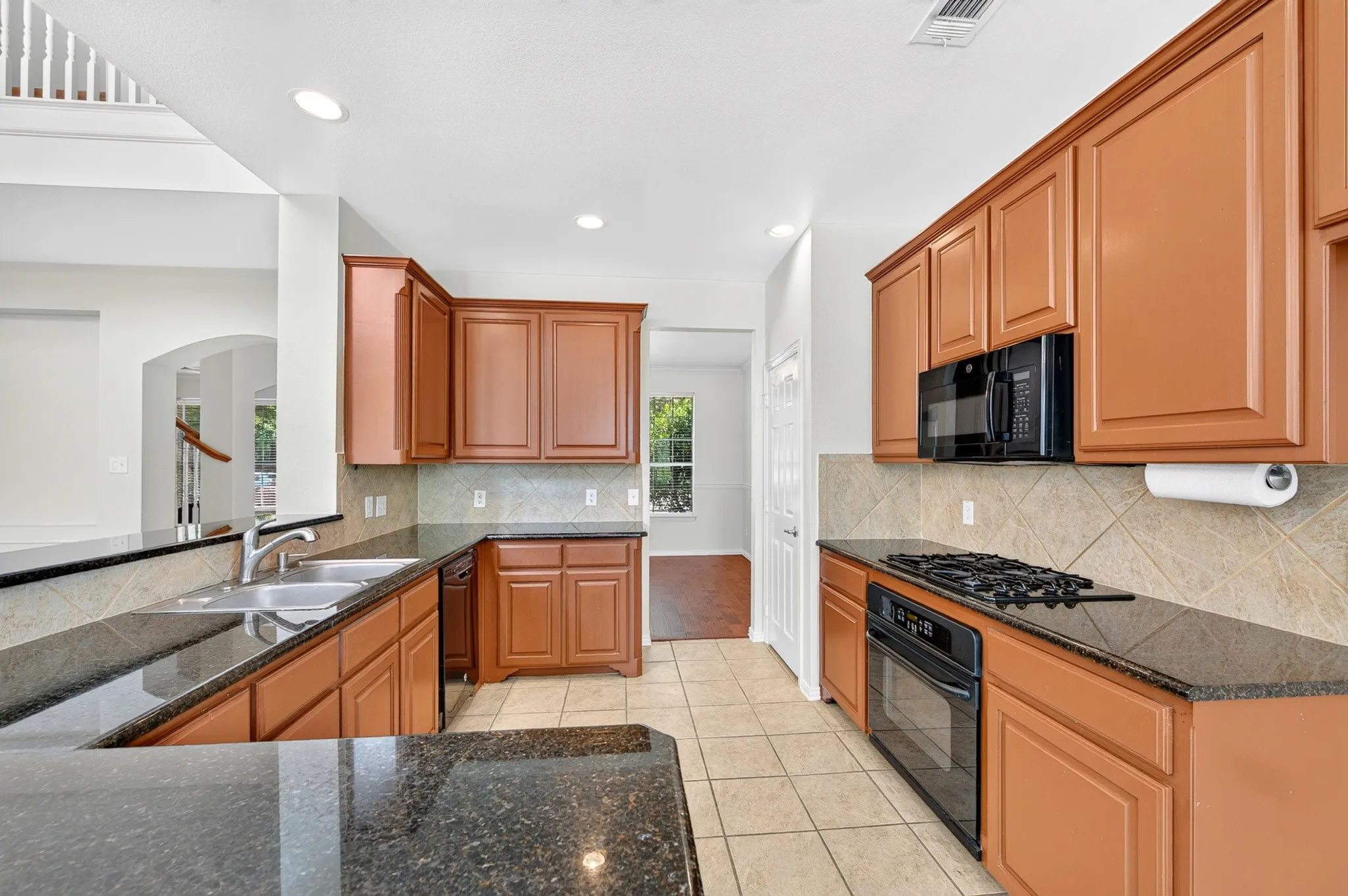 Kitchen featuring rich wood cabinetry, dark speckled countertops, and a neutral-toned tile backsplash