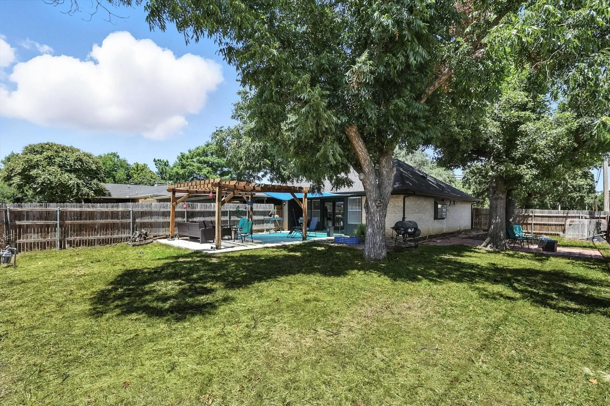 Expansive backyard with a manicured lawn, established trees, and wood privacy fencing
