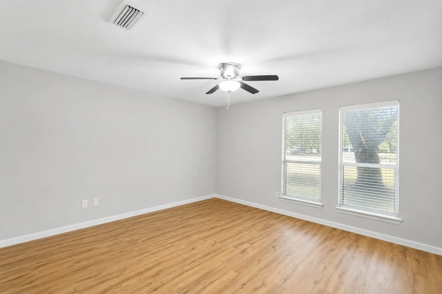 Spacious room featuring wood-finish flooring, light gray walls, and bright white trim
