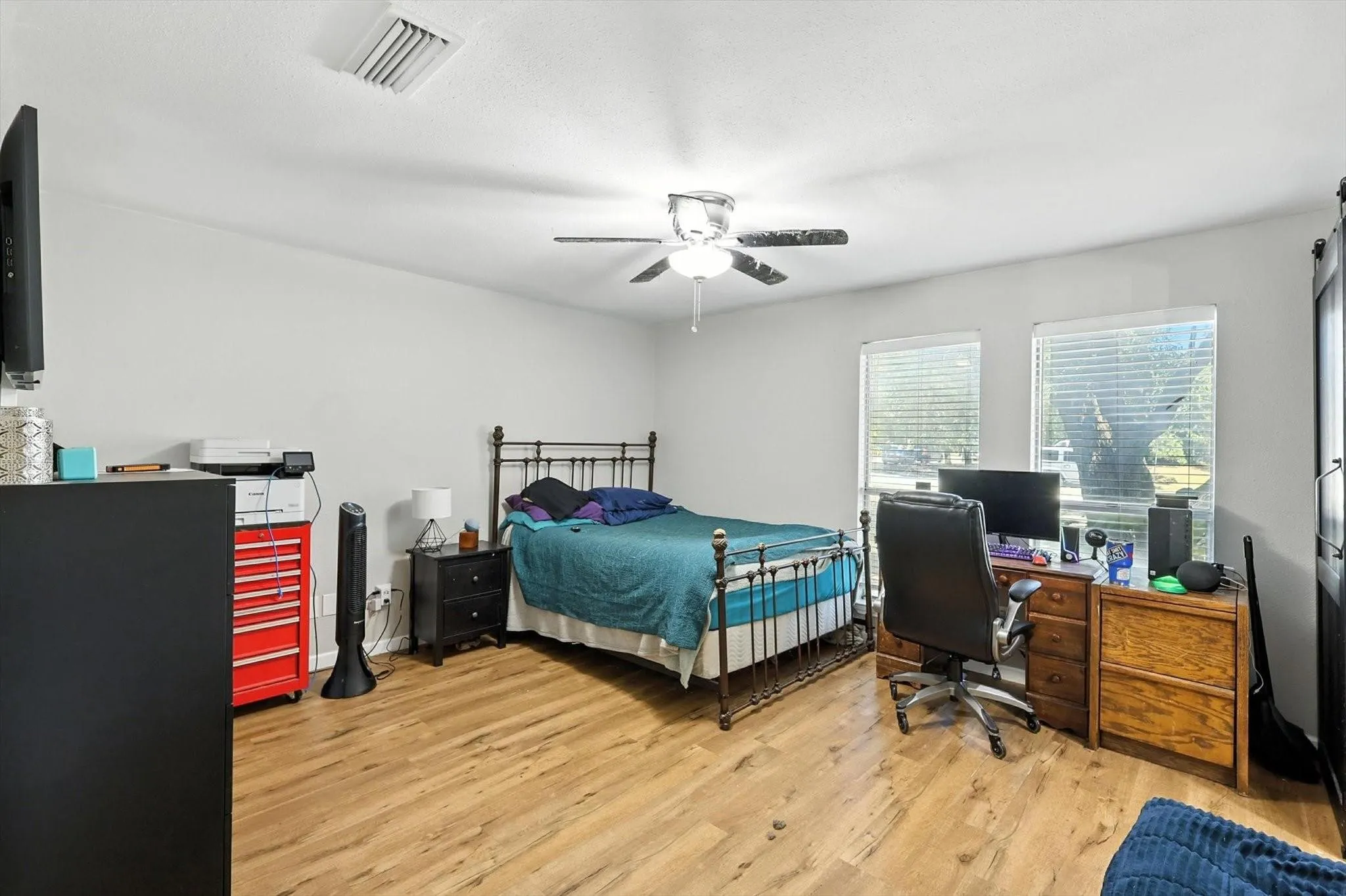 Wood-finish flooring, white walls, and a ceiling fan with integrated lighting