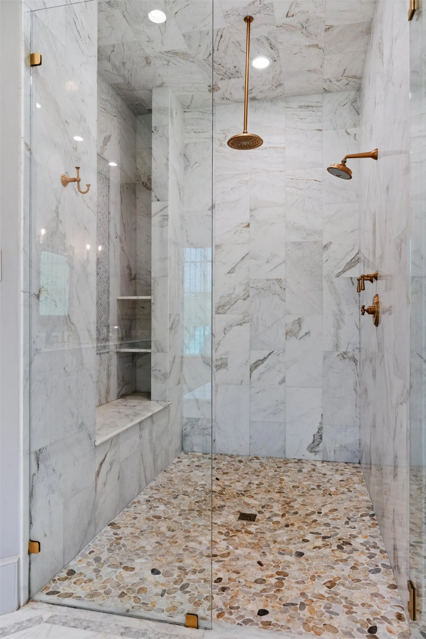 Incredible hand laid marble surround with designer brass hardware and bench seating complete this oasis.