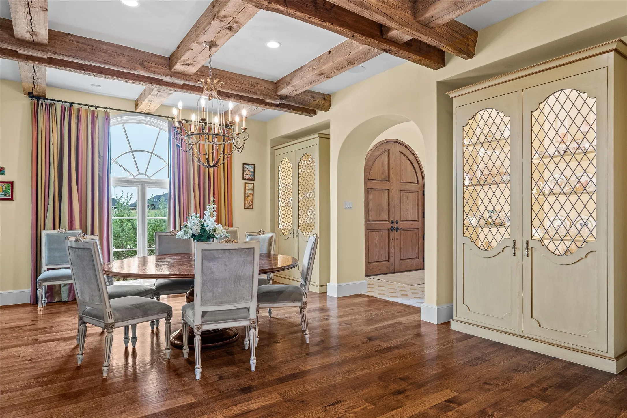 Enhanced by rough hewn, reclaimed wooden beams, the formal dining area enjoys warm wood floors and built in display cabinets.
