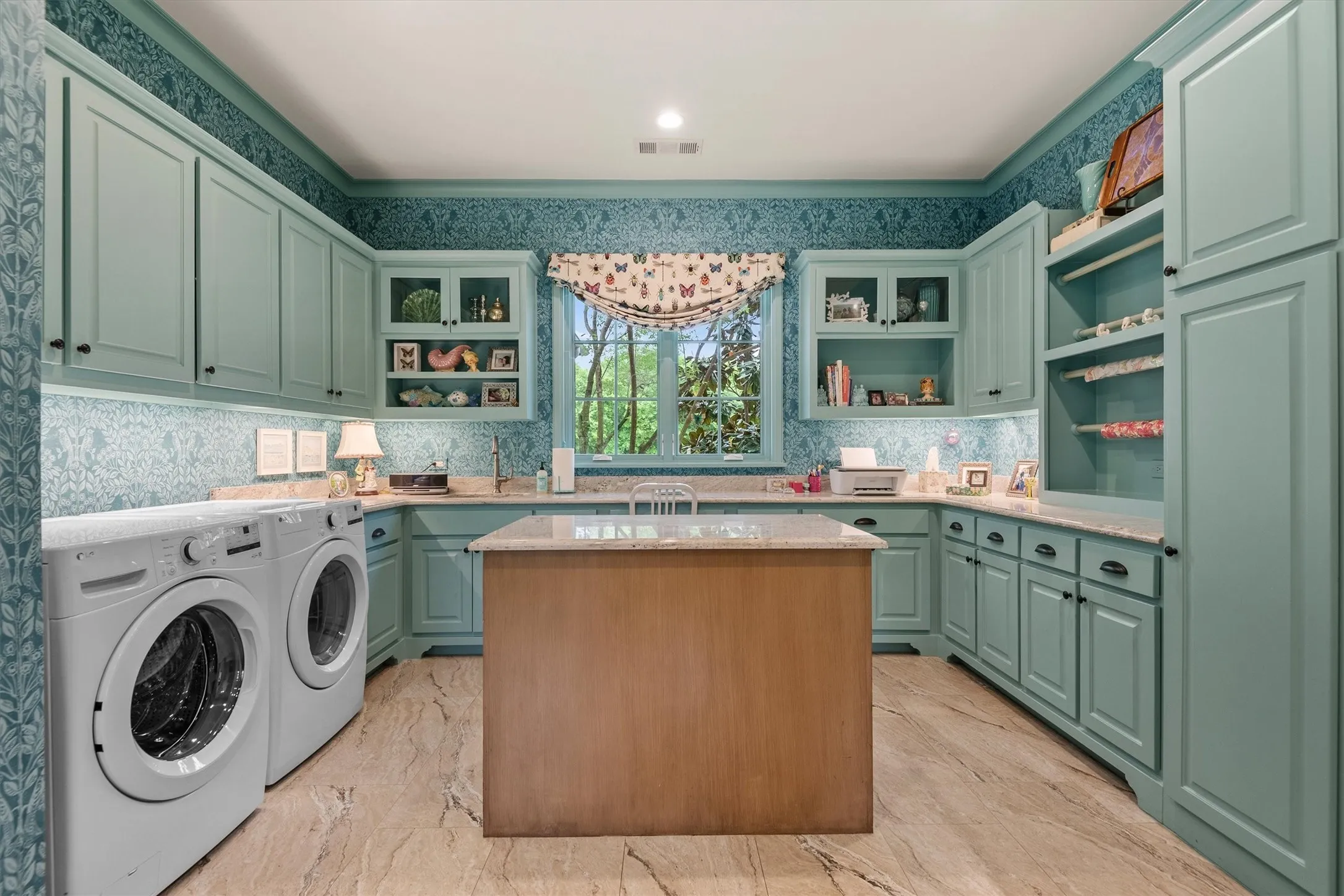 The utility room  also doubles as a craft room--with an abundance of cabinets, counter space and an island, the possibilities are endless for your fueling your creative hobbies.
