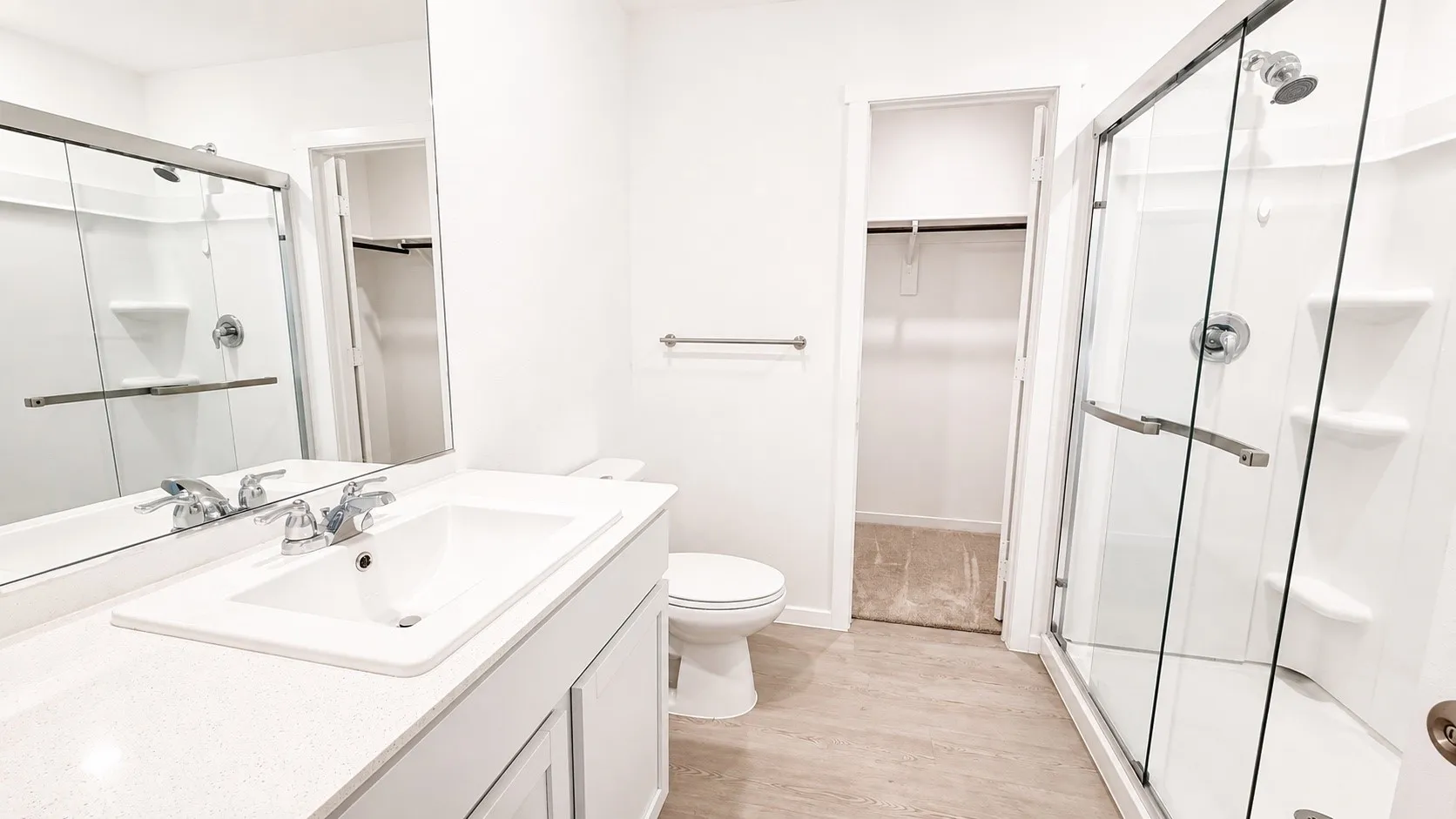 Bathroom featuring a glass-enclosed shower, white vanity with an integrated sink, polished chrome fixtures, and a large wall-mounted mirror