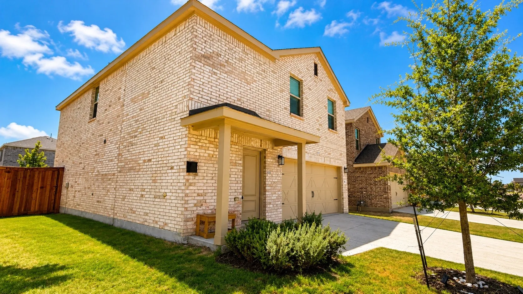 Two-story brick exterior, attached two-car garage, covered front porch, concrete driveway, and a fenced backyard