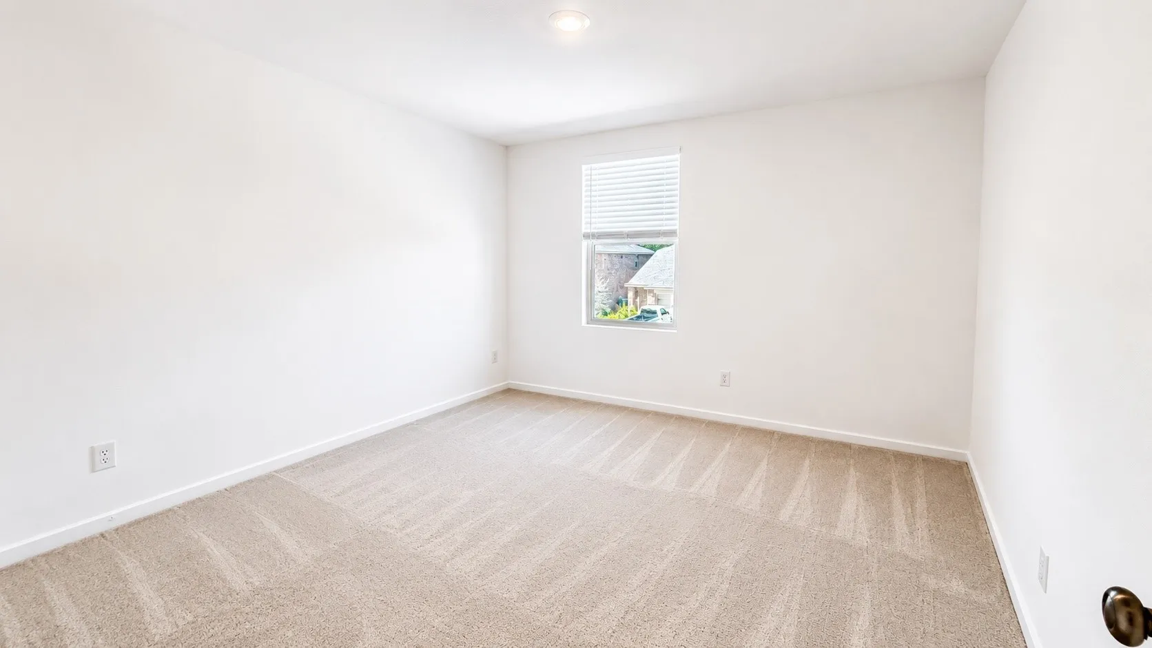 Neutral color palette, window with horizontal blinds, overhead lighting, carpeted flooring