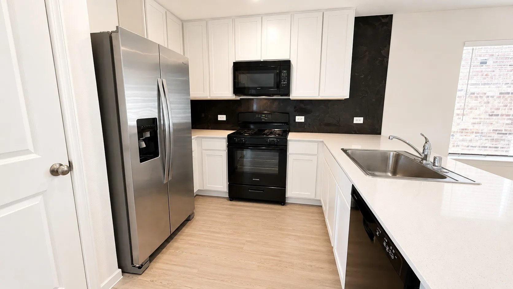 Kitchen featuring white cabinetry, light-toned wood-finish flooring, stainless steel side-by-side refrigerator, white countertops, and a stainless steel sink